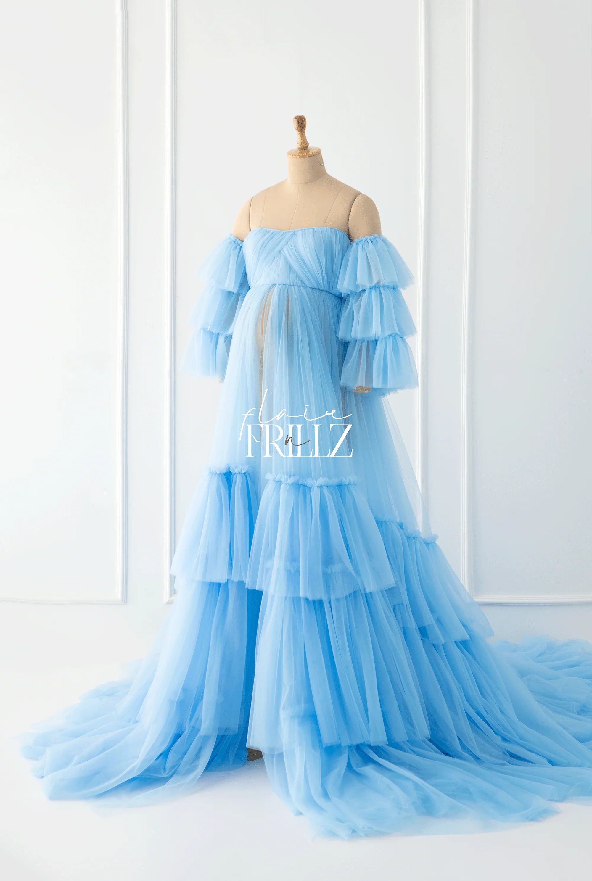 Light blue ruffled maternity gown with layered tulle on a dress form in a bright room