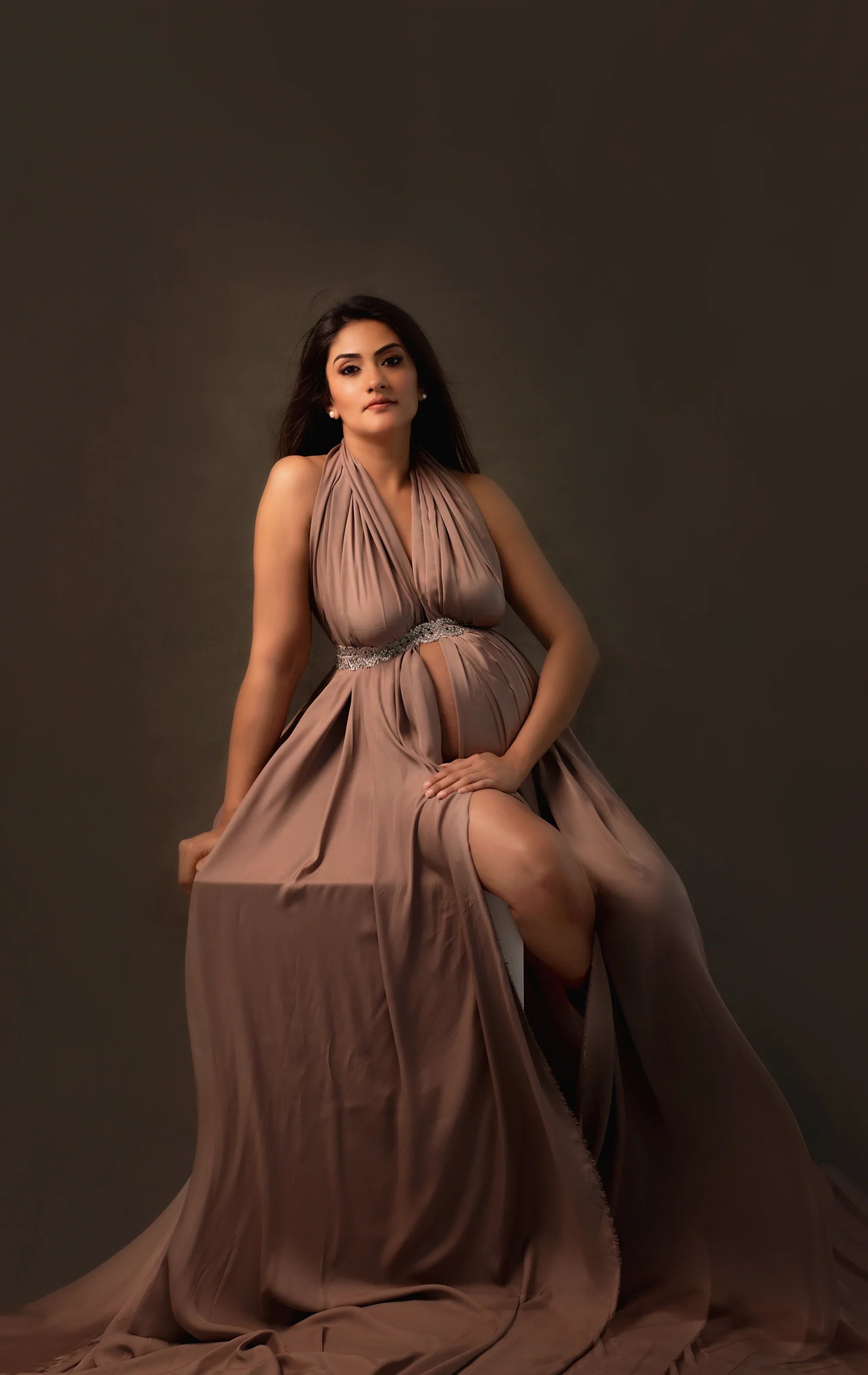Elegant maternity gown in taupe with halter neck, flowing skirt, and jeweled waist detail