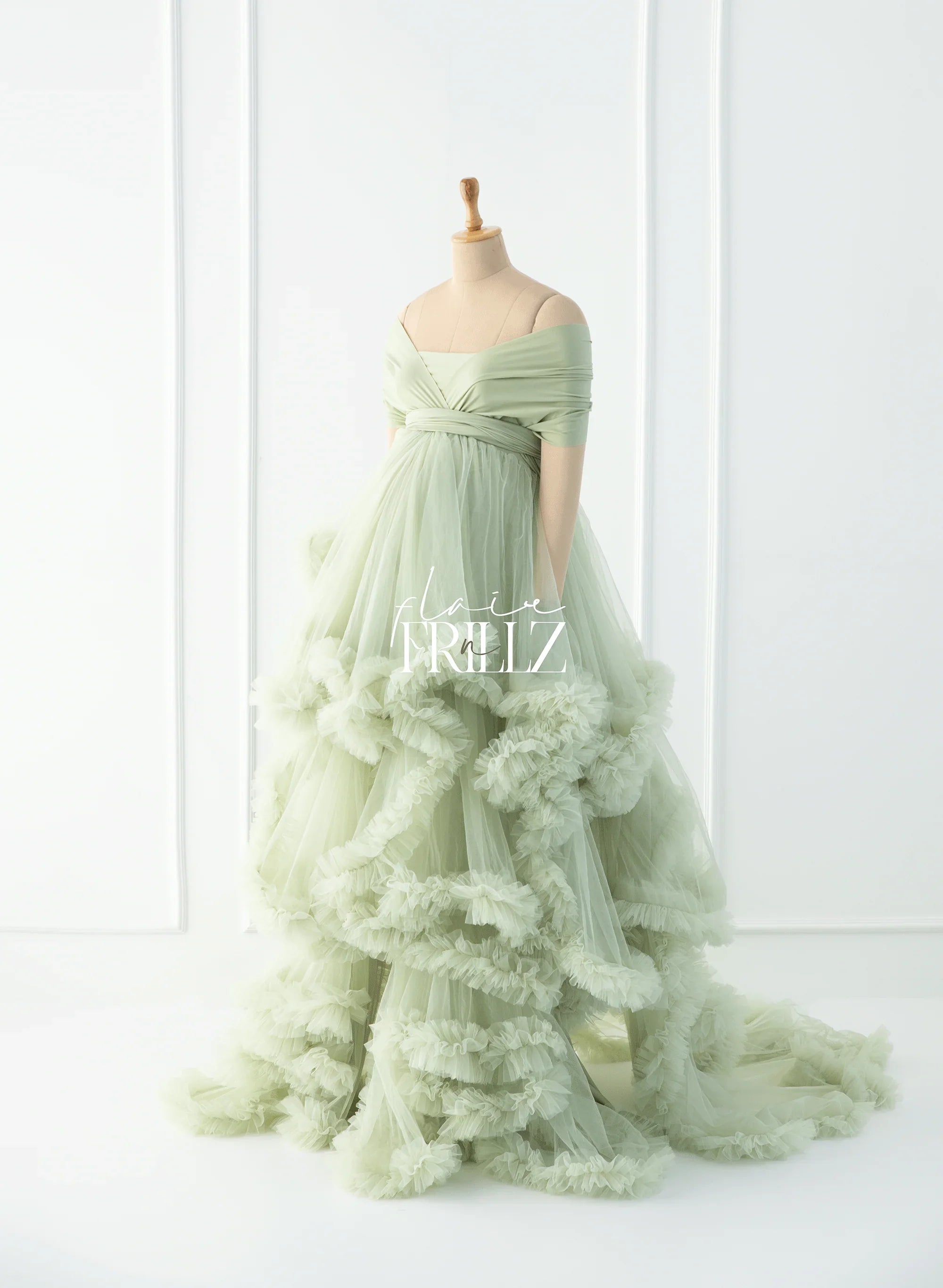 Elegant sage green off-shoulder maternity gown with layered ruffle tulle skirt on mannequin