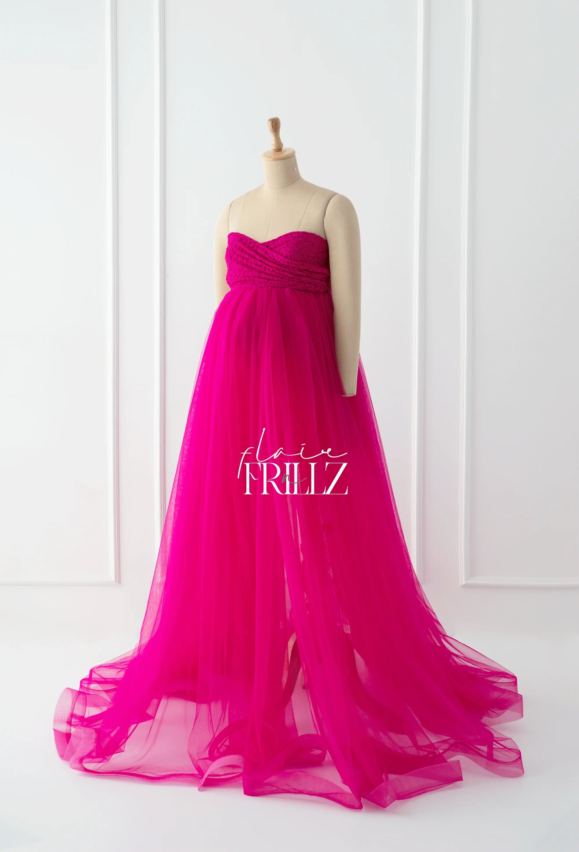 Hot pink strapless maternity gown with flowing tulle skirt on mannequin in studio