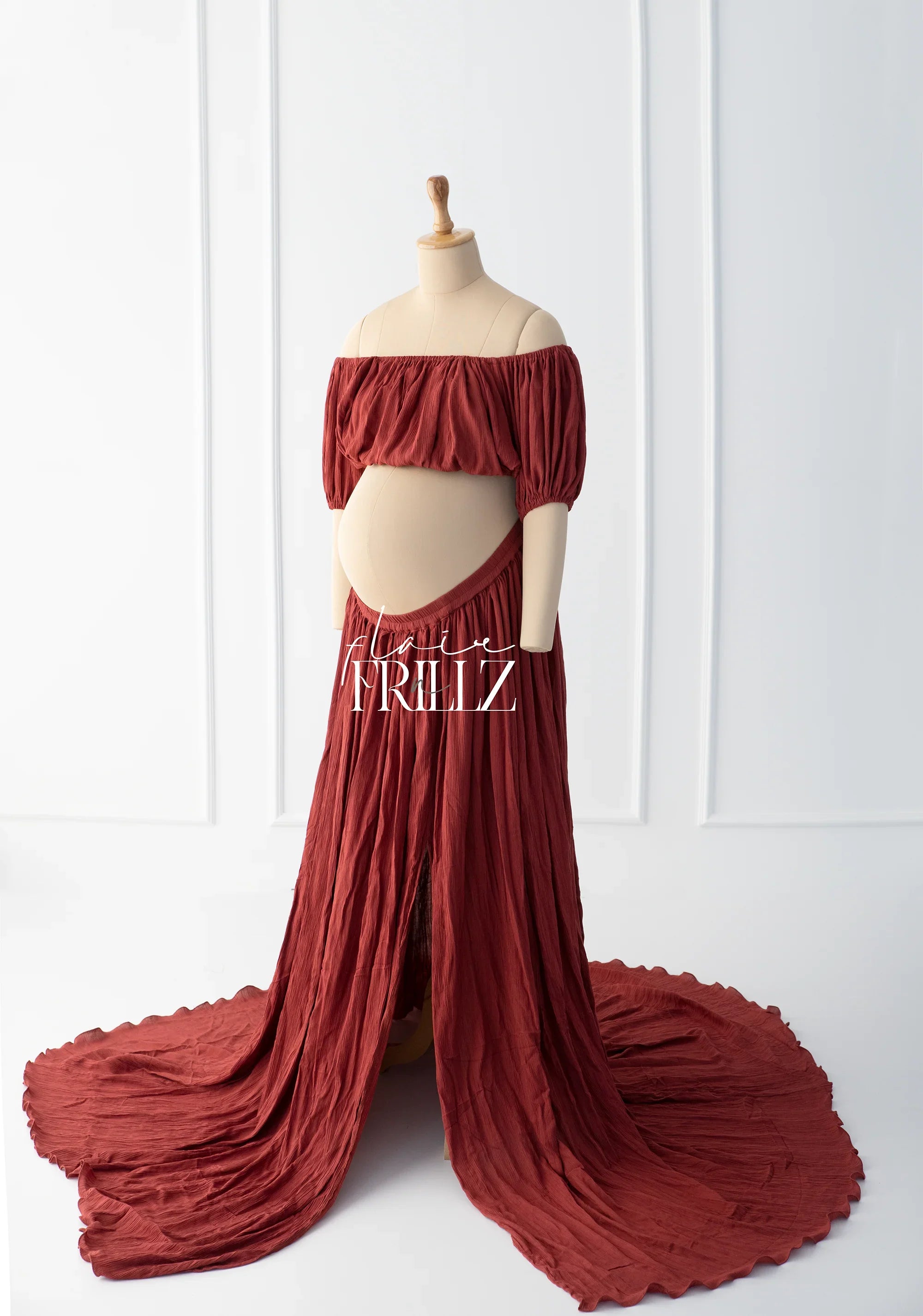 Boho-style off-shoulder rust maternity gown on mannequin with flowing skirt