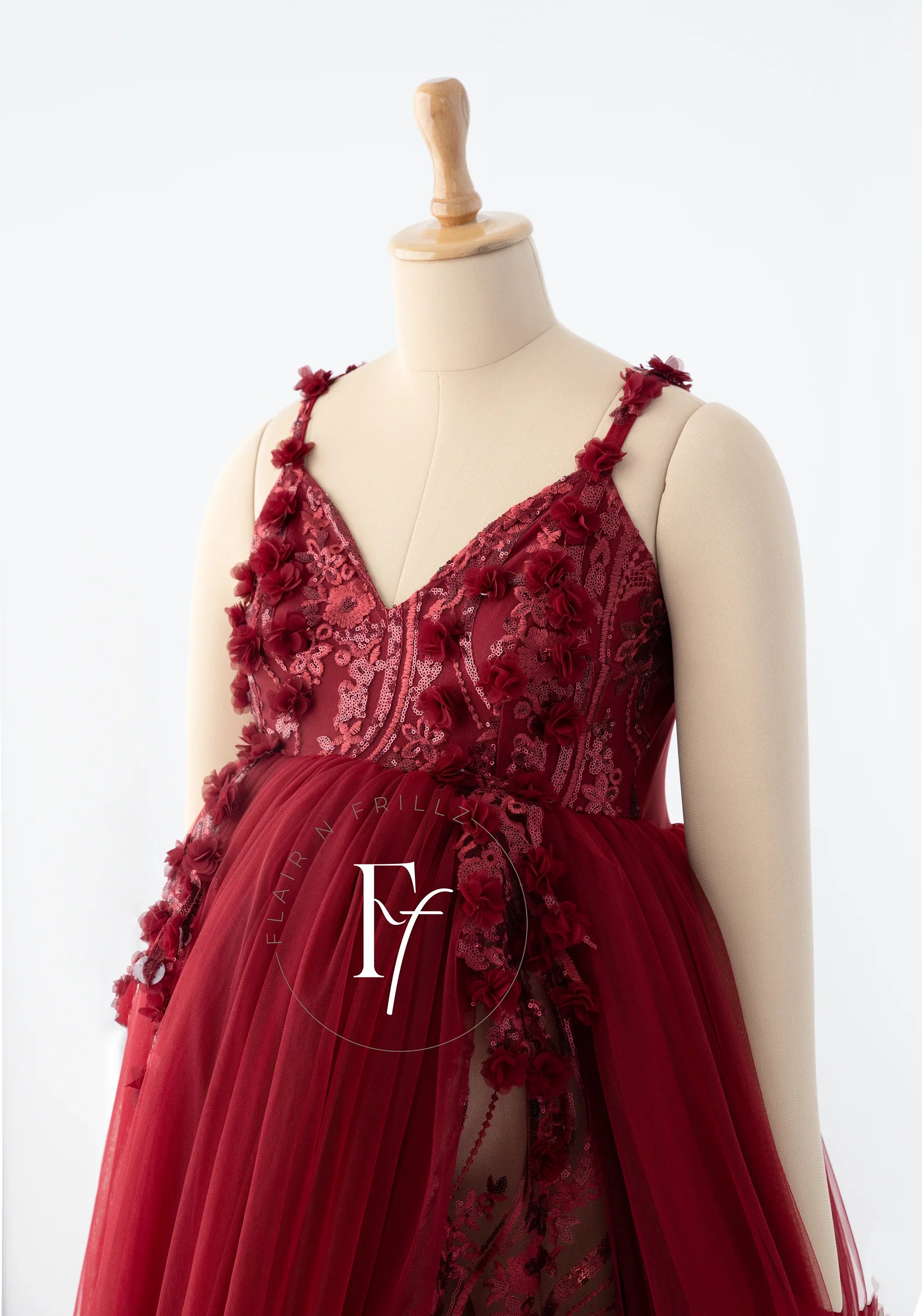 Elegant burgundy maternity gown with floral lace details and tulle skirt on mannequin