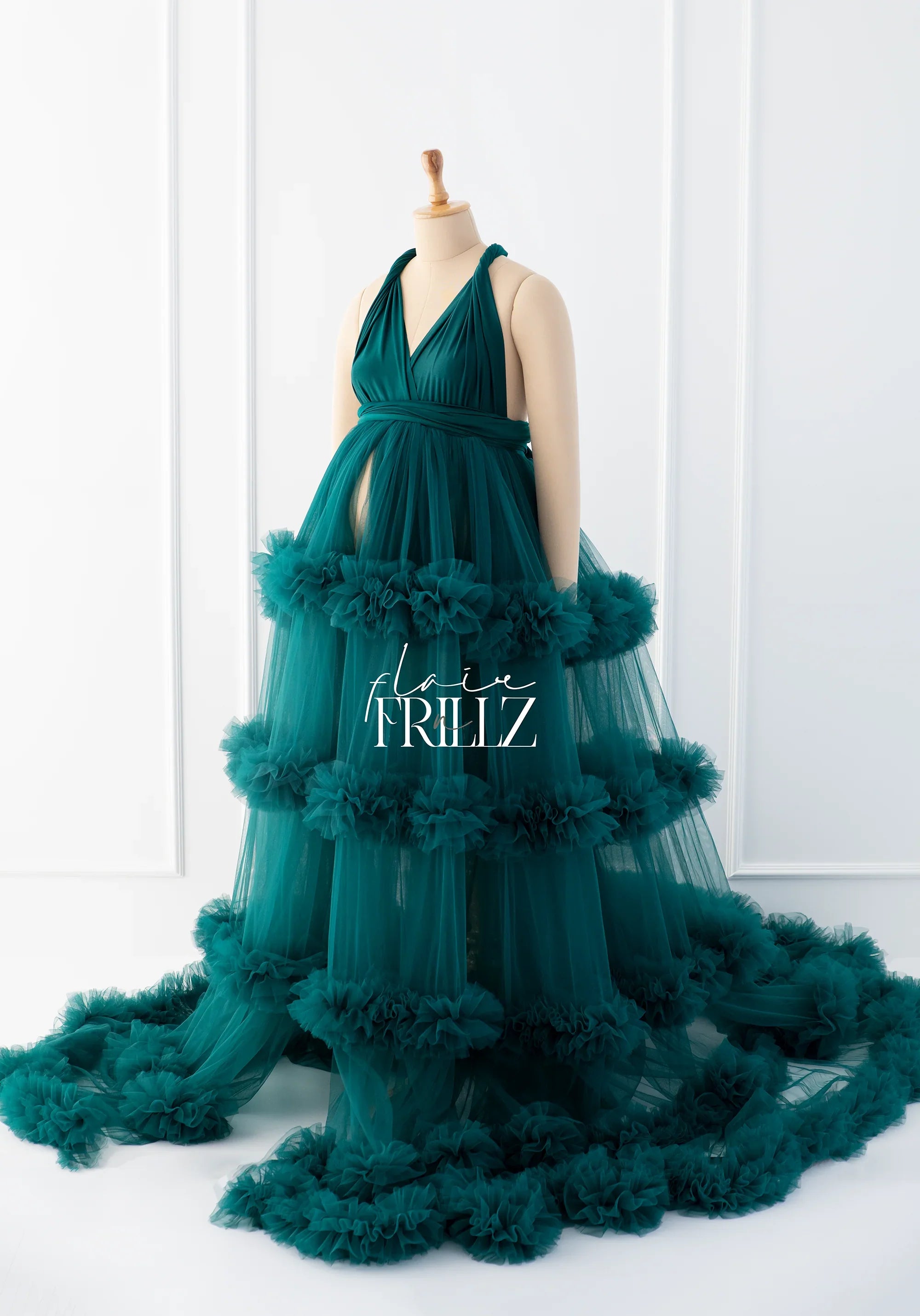 Elegant green maternity gown with ruffled tulle layers on a mannequin