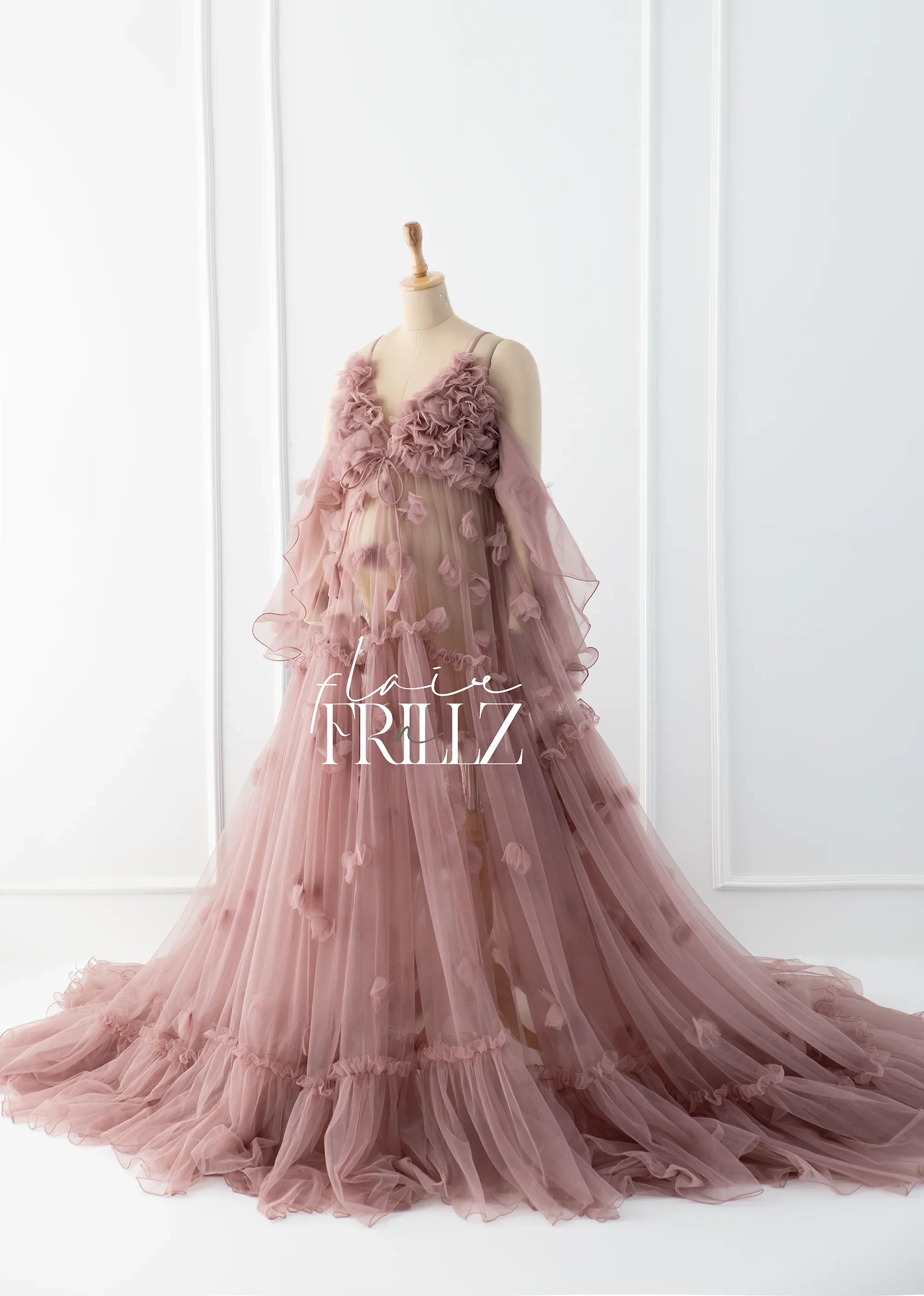 Long mauve sheer maternity gown with floral details displayed on a mannequin in a bright room.