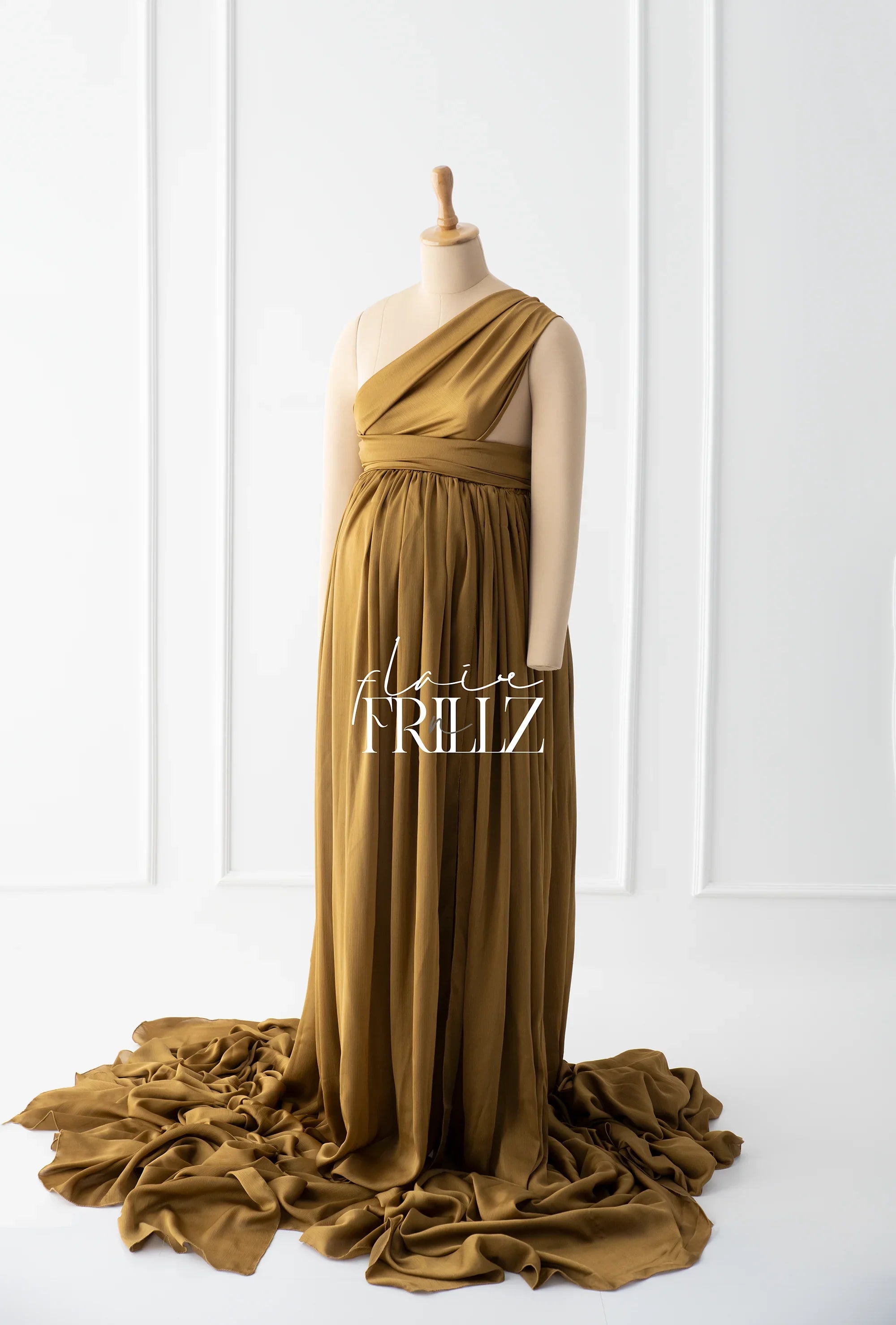 One-shoulder silky maternity gown in gold, floor-length with flowing train on a mannequin.
