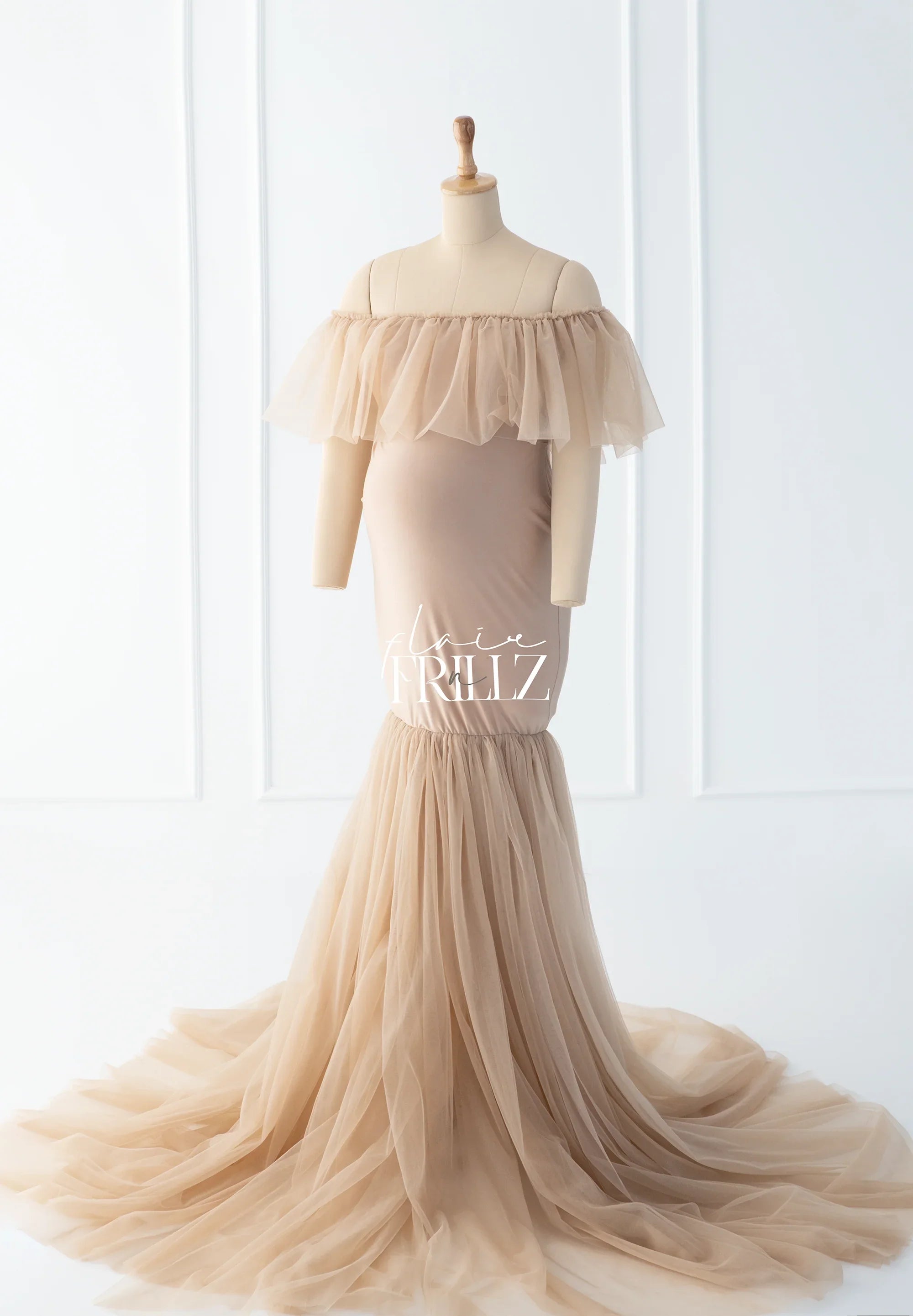 Beige off-shoulder maternity gown with tulle ruffle details and mermaid silhouette on mannequin