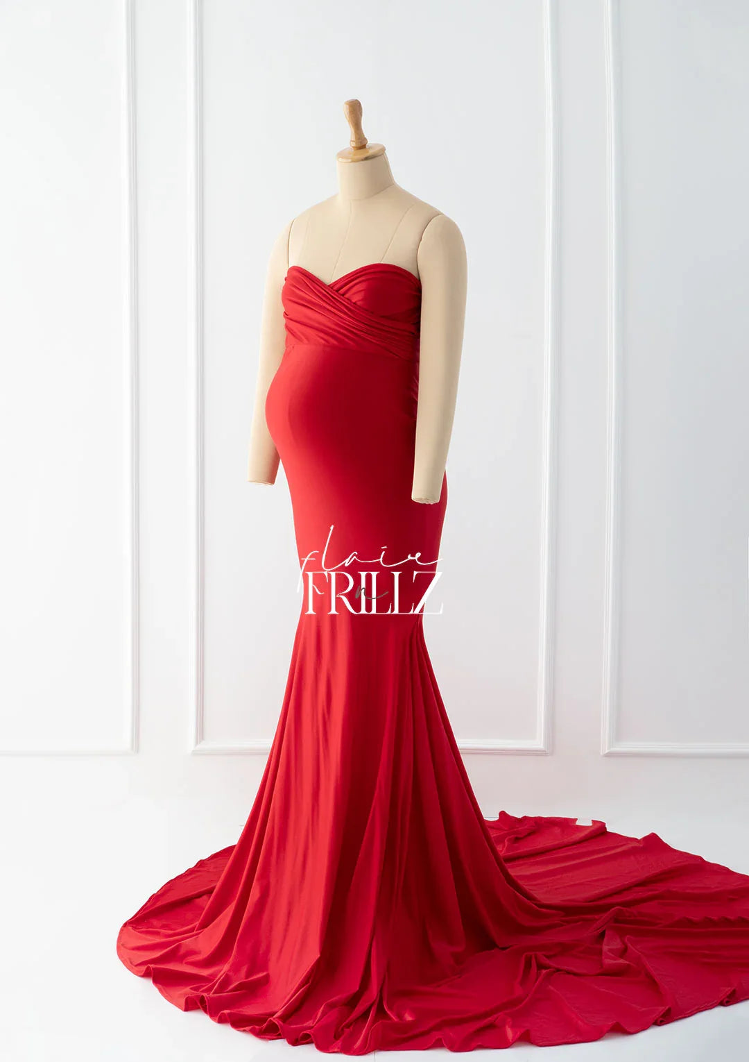 Red strapless maternity gown with ruched bodice on mannequin, flowing floor-length skirt