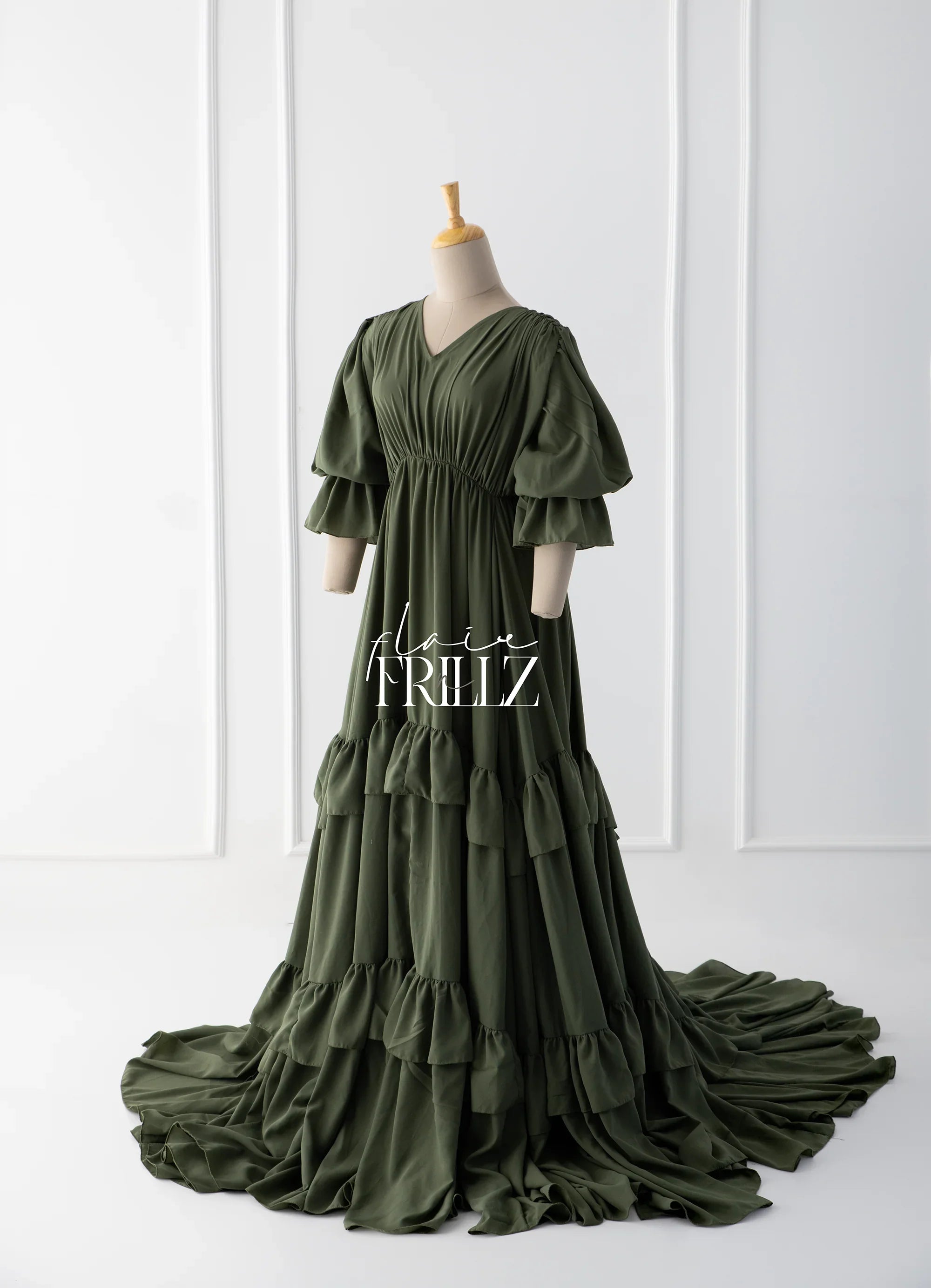 Olive green boho maternity gown with ruffled tiers and puff sleeves on mannequin