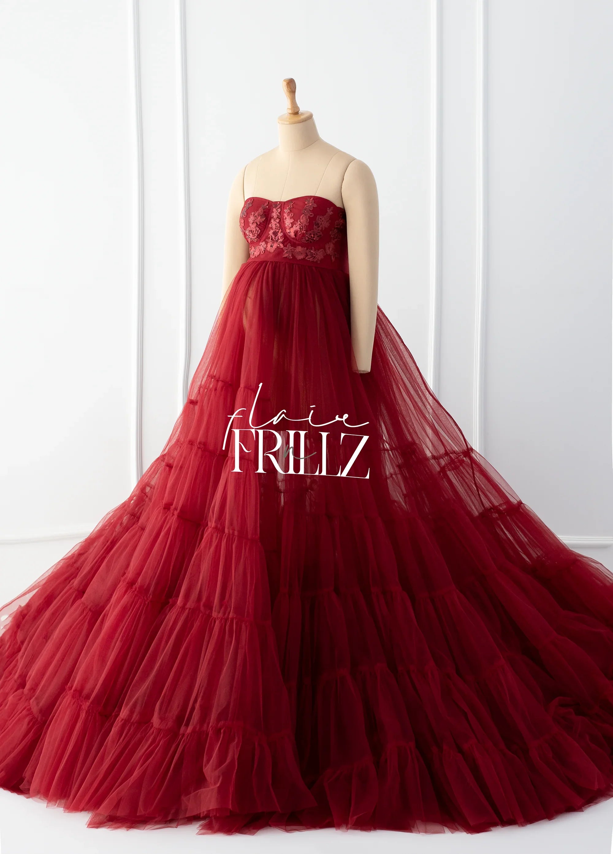 Elegant burgundy maternity gown with tulle skirt and embroidered bodice on mannequin
