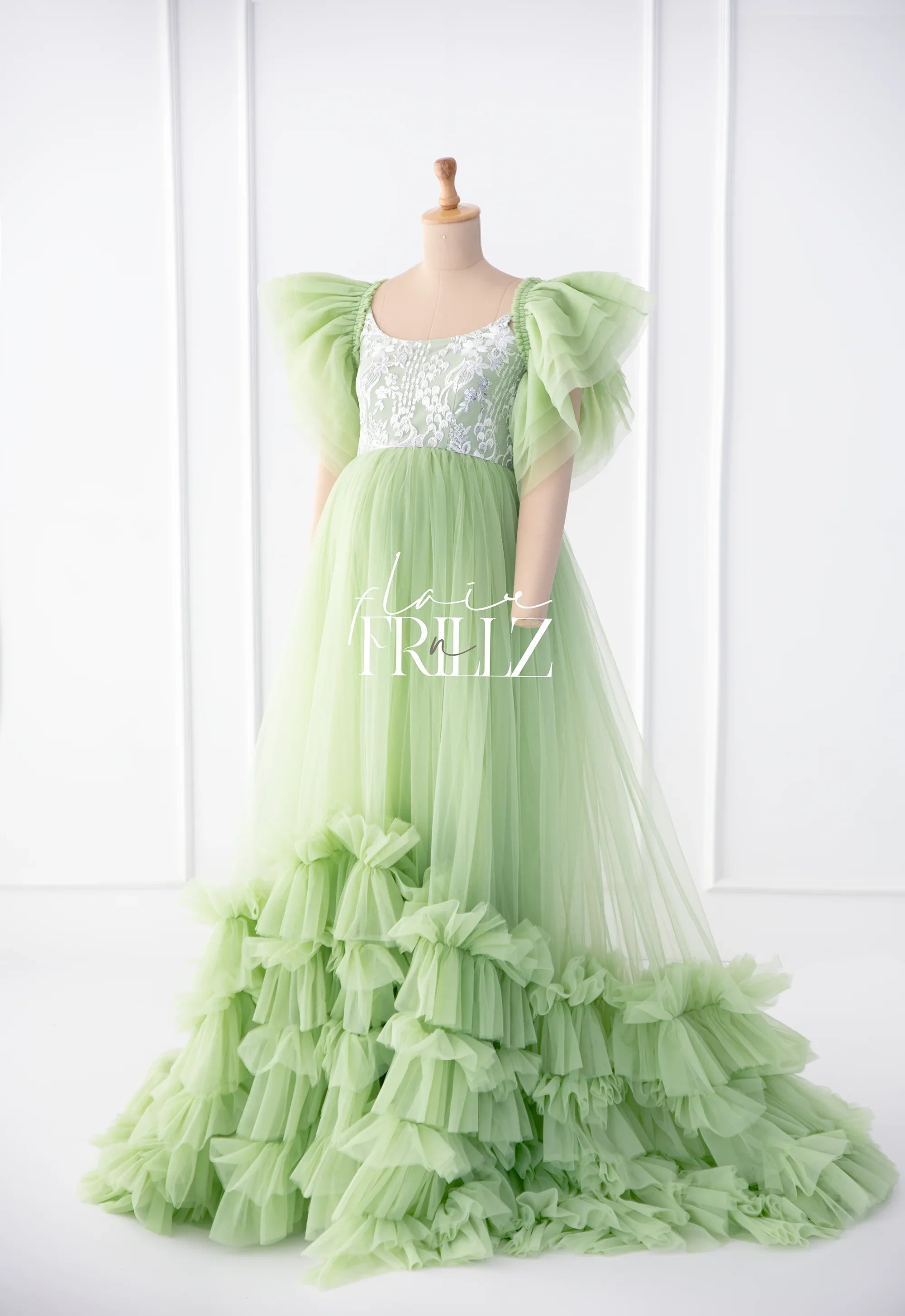 Light green maternity gown with ruffled tulle skirt and lace bodice on mannequin