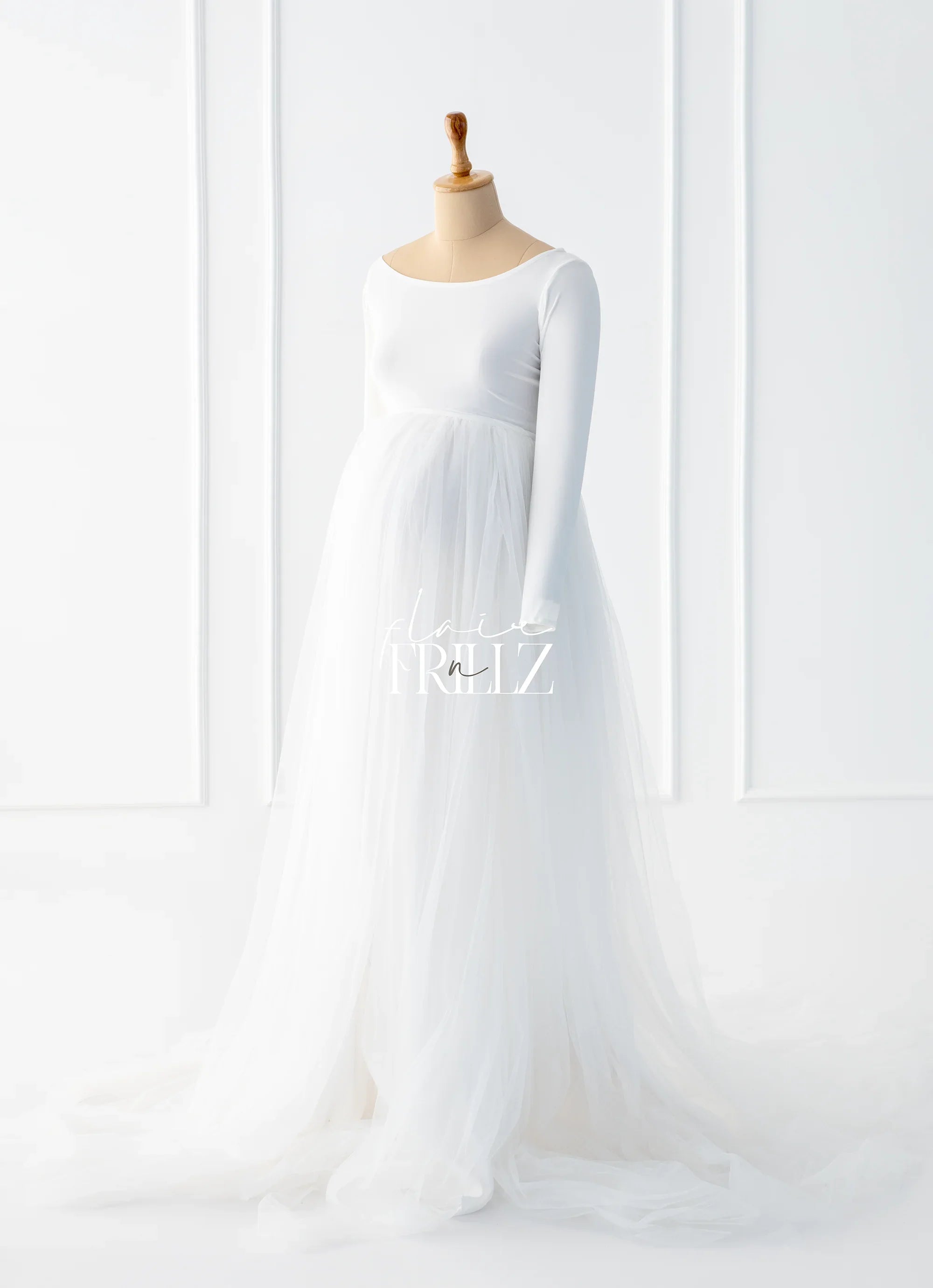 Elegant white long-sleeve maternity gown with tulle skirt on mannequin