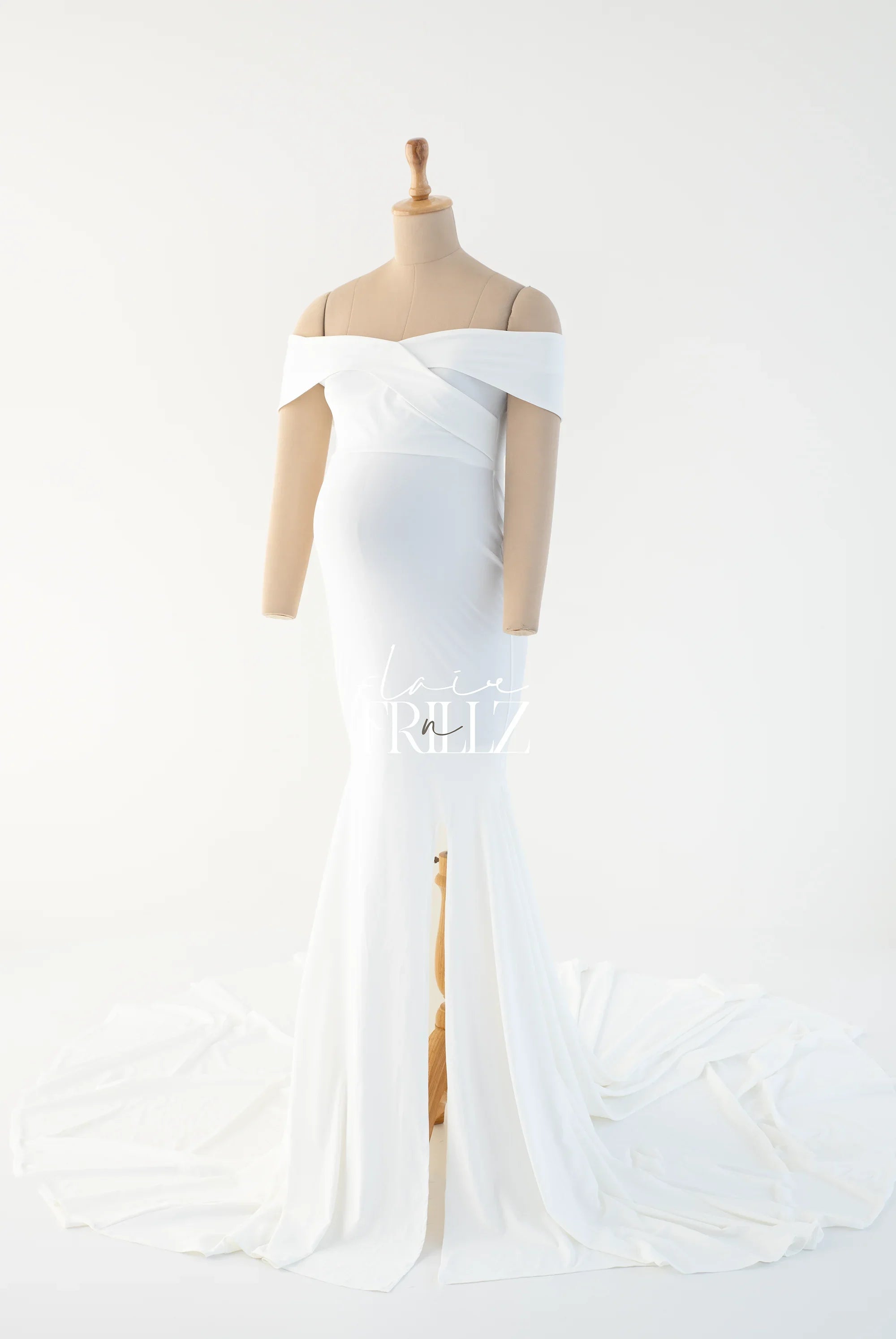 White off-shoulder maternity gown with fitted bodice and flowing train on mannequin