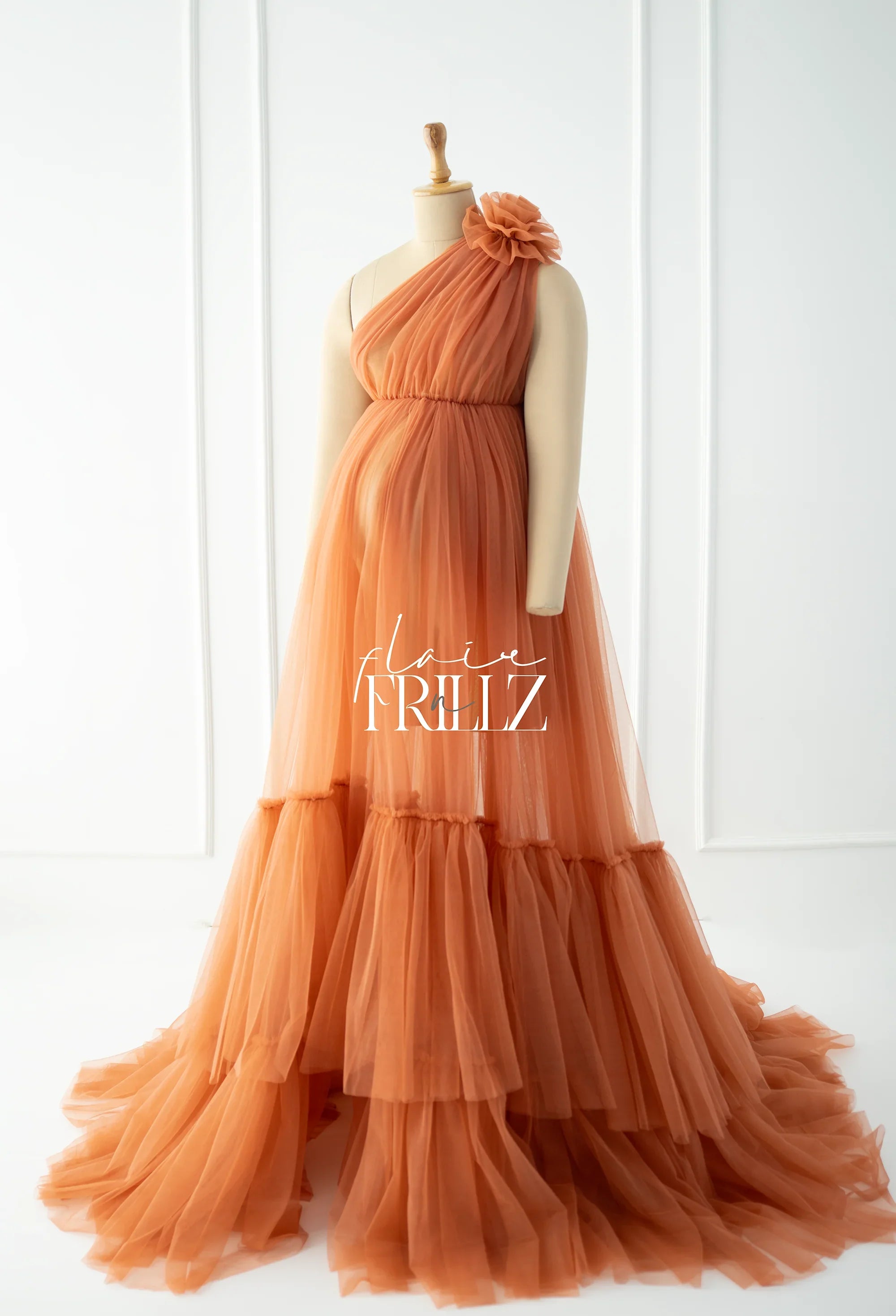 Peach tulle maternity gown with one-shoulder floral detail on a mannequin