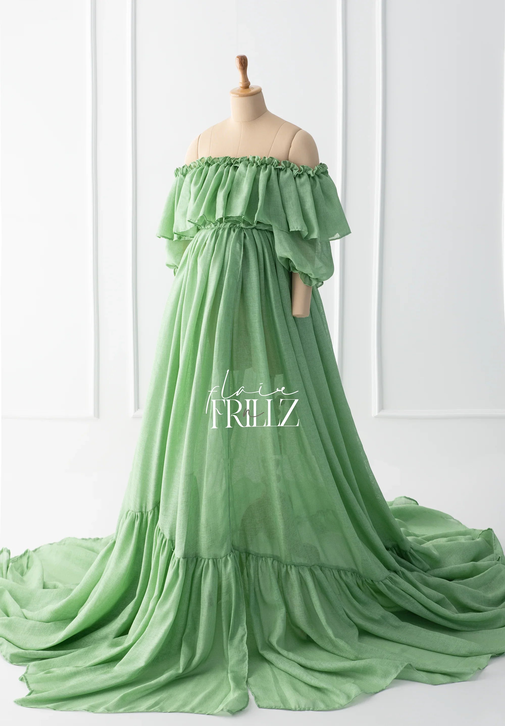 Sage green off-shoulder maternity gown with ruffle sleeves and floor-length skirt on mannequin