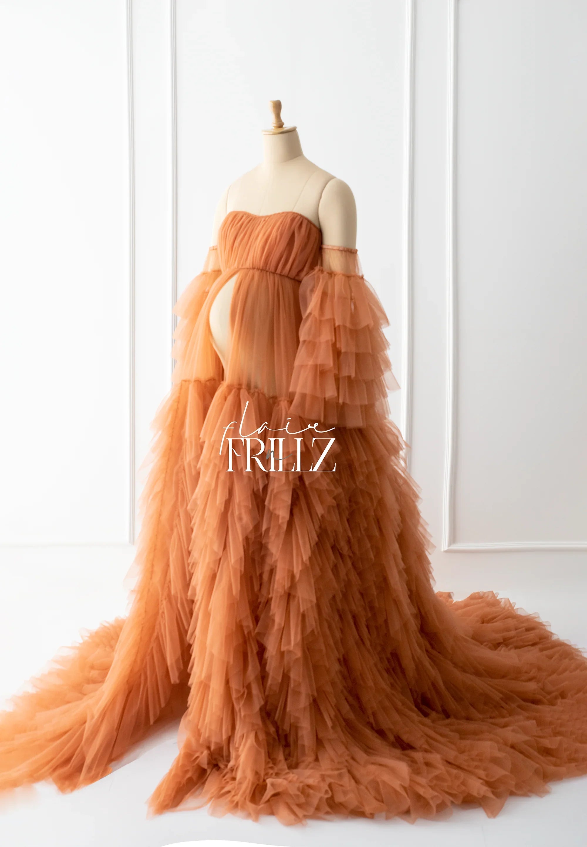 Rust orange ruffled tulle maternity gown with off-shoulder sleeves and long train on mannequin