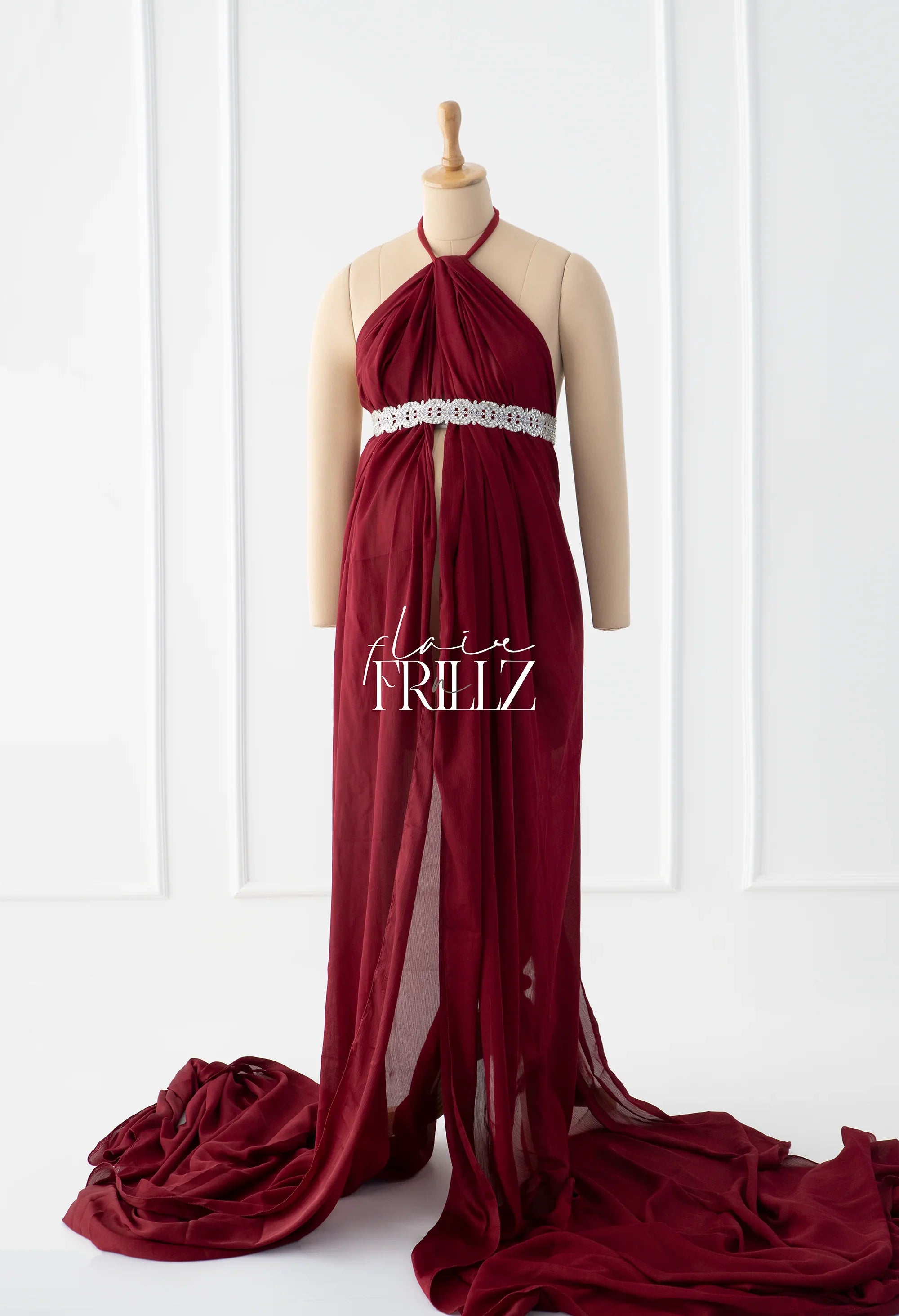 Burgundy maternity gown with halter neck and lace belt displayed on a mannequin