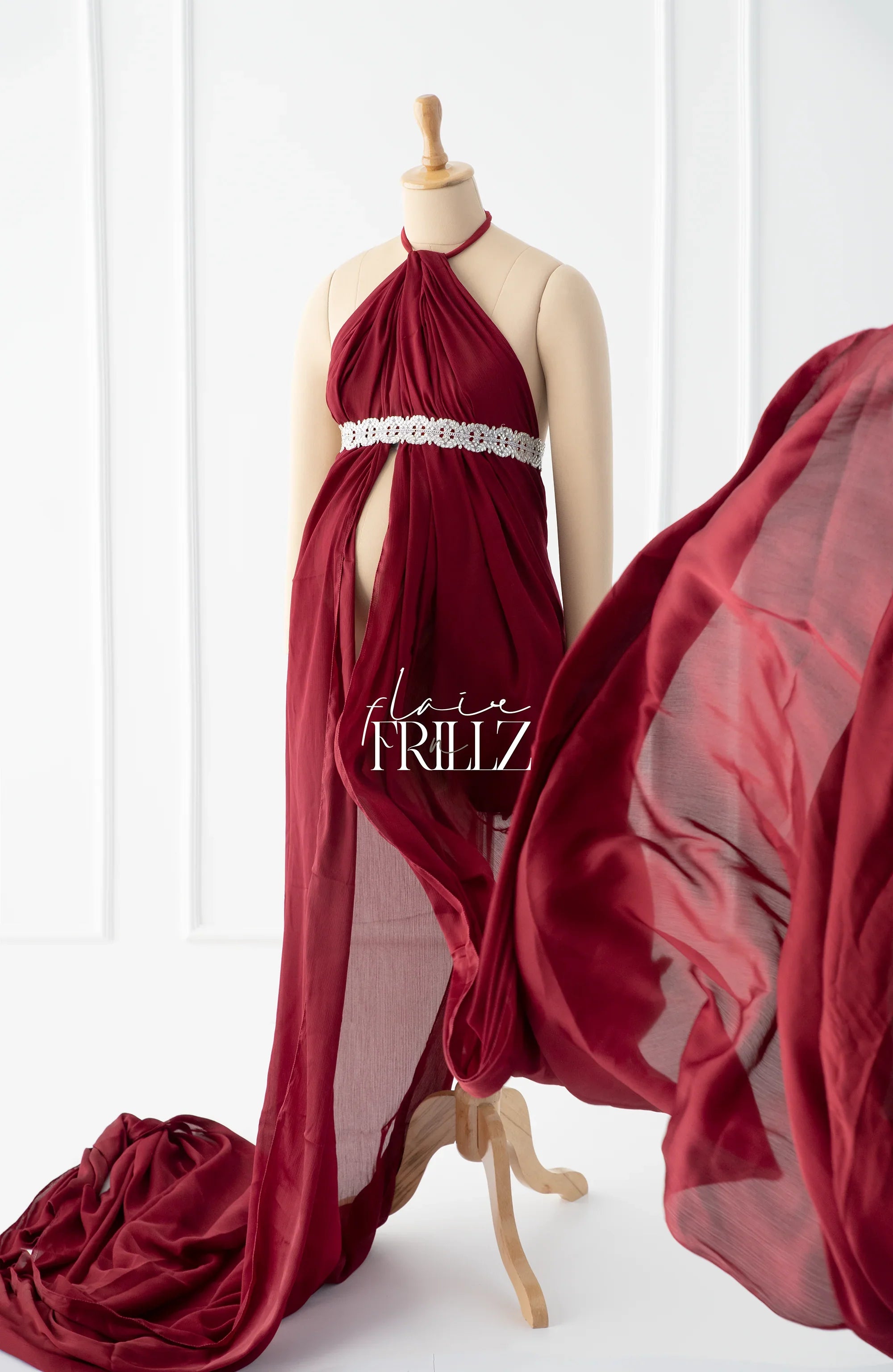 Burgundy maternity gown with flowing chiffon fabric and jeweled waistband on mannequin