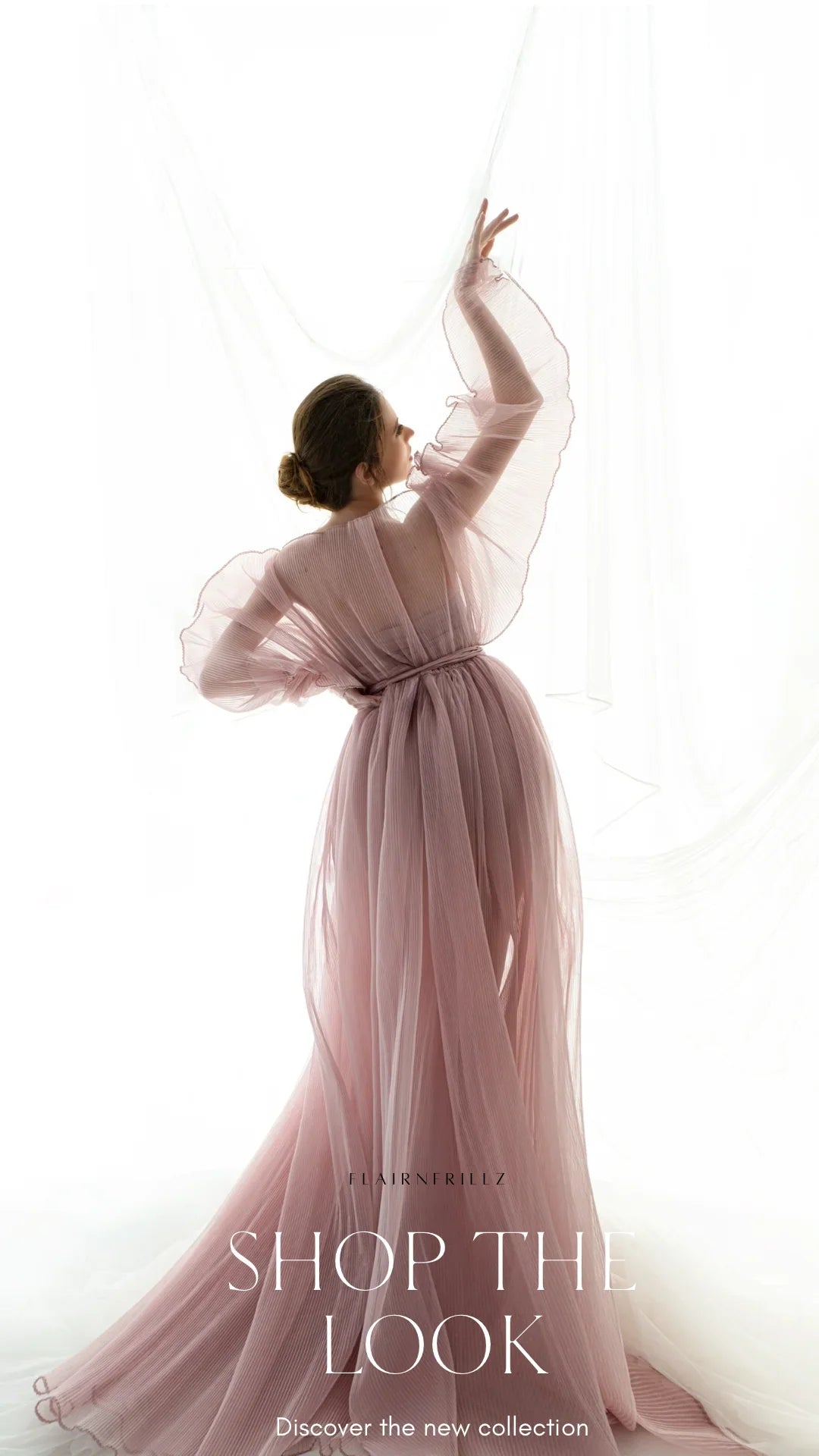 Woman in flowing sheer pink maternity gown posing gracefully in soft natural light