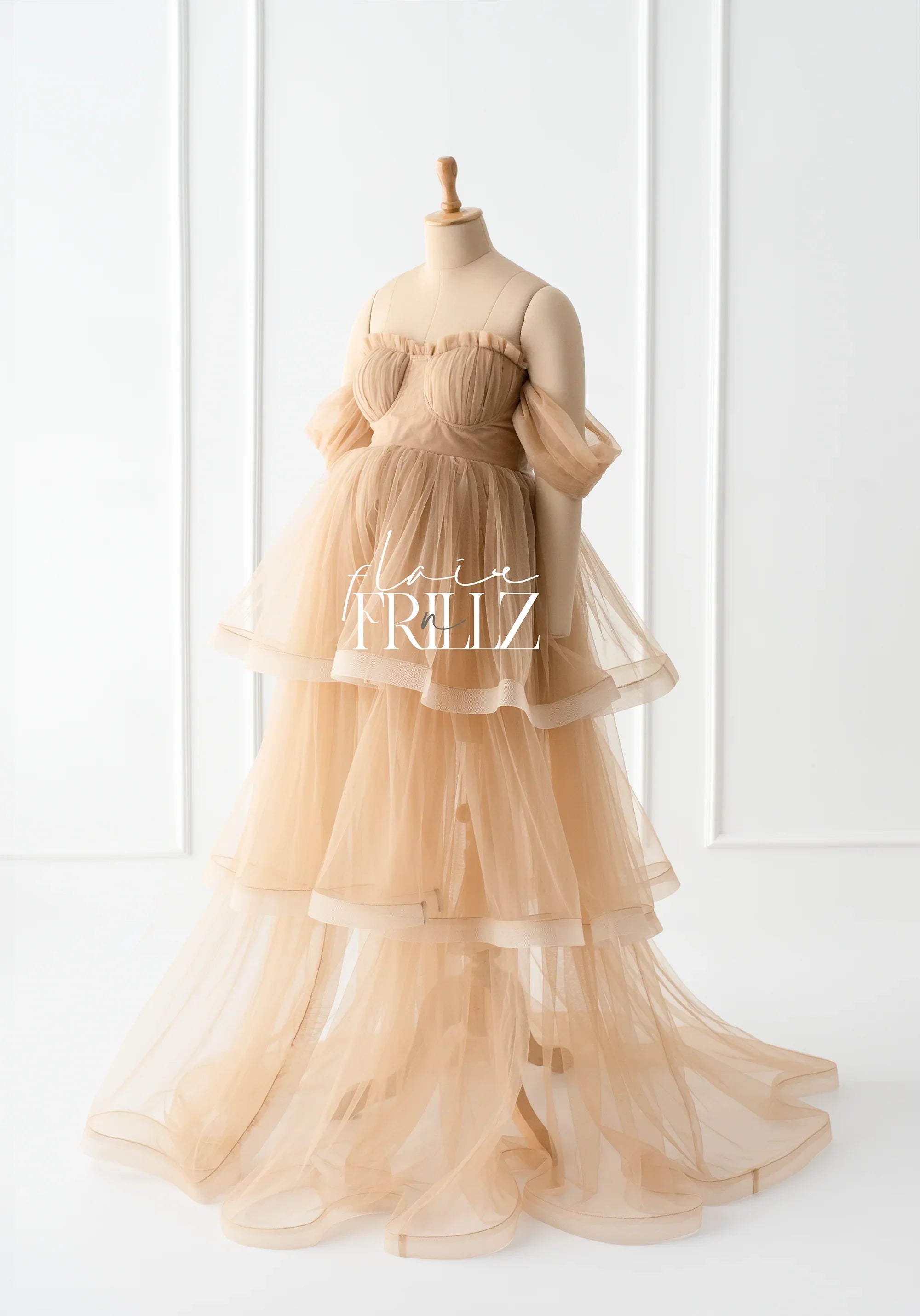 Sheer beige layered maternity gown with off-shoulder tulle sleeves on a mannequin