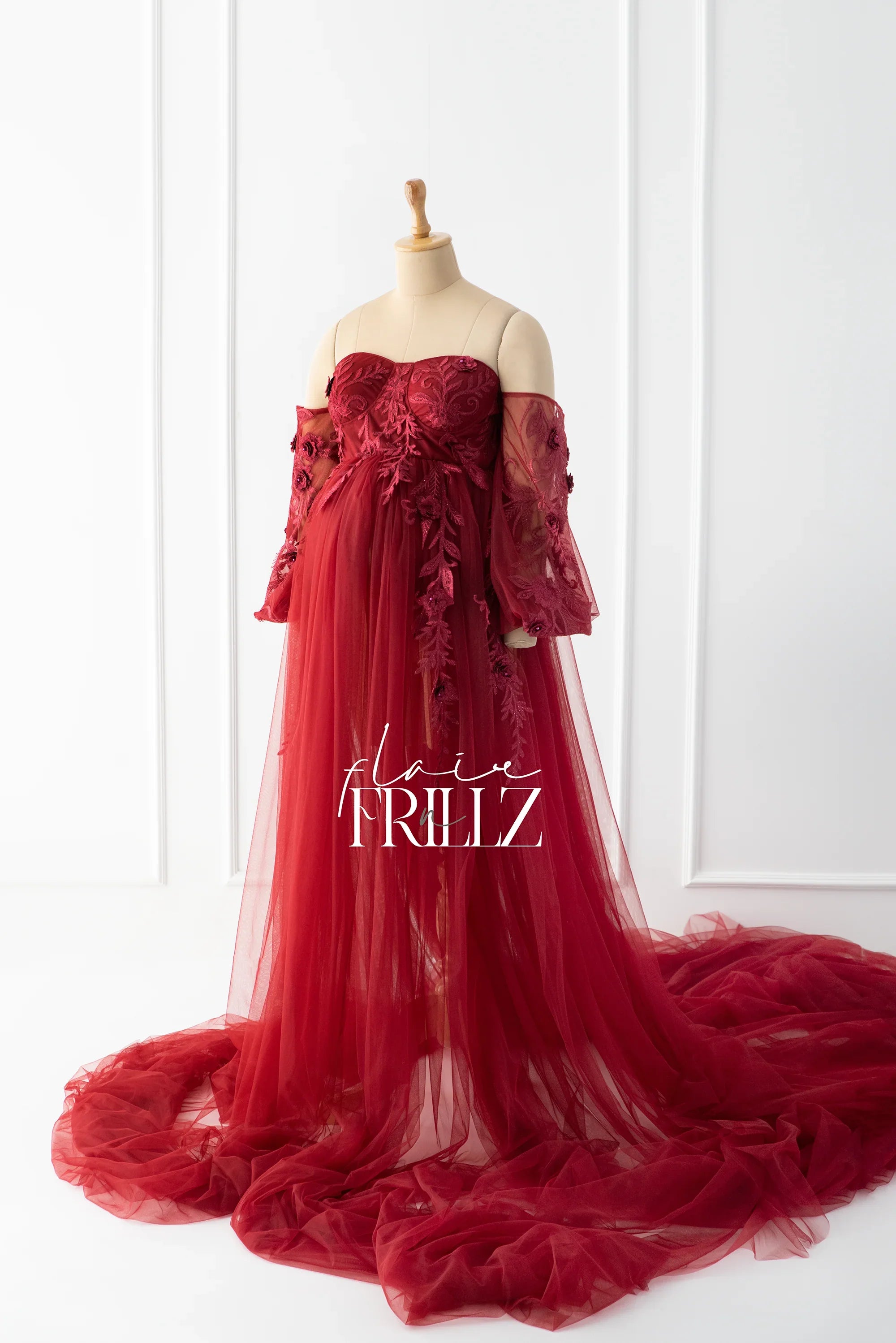 Elegant burgundy maternity gown with floral lace, sheer long sleeves, and flowing tulle skirt