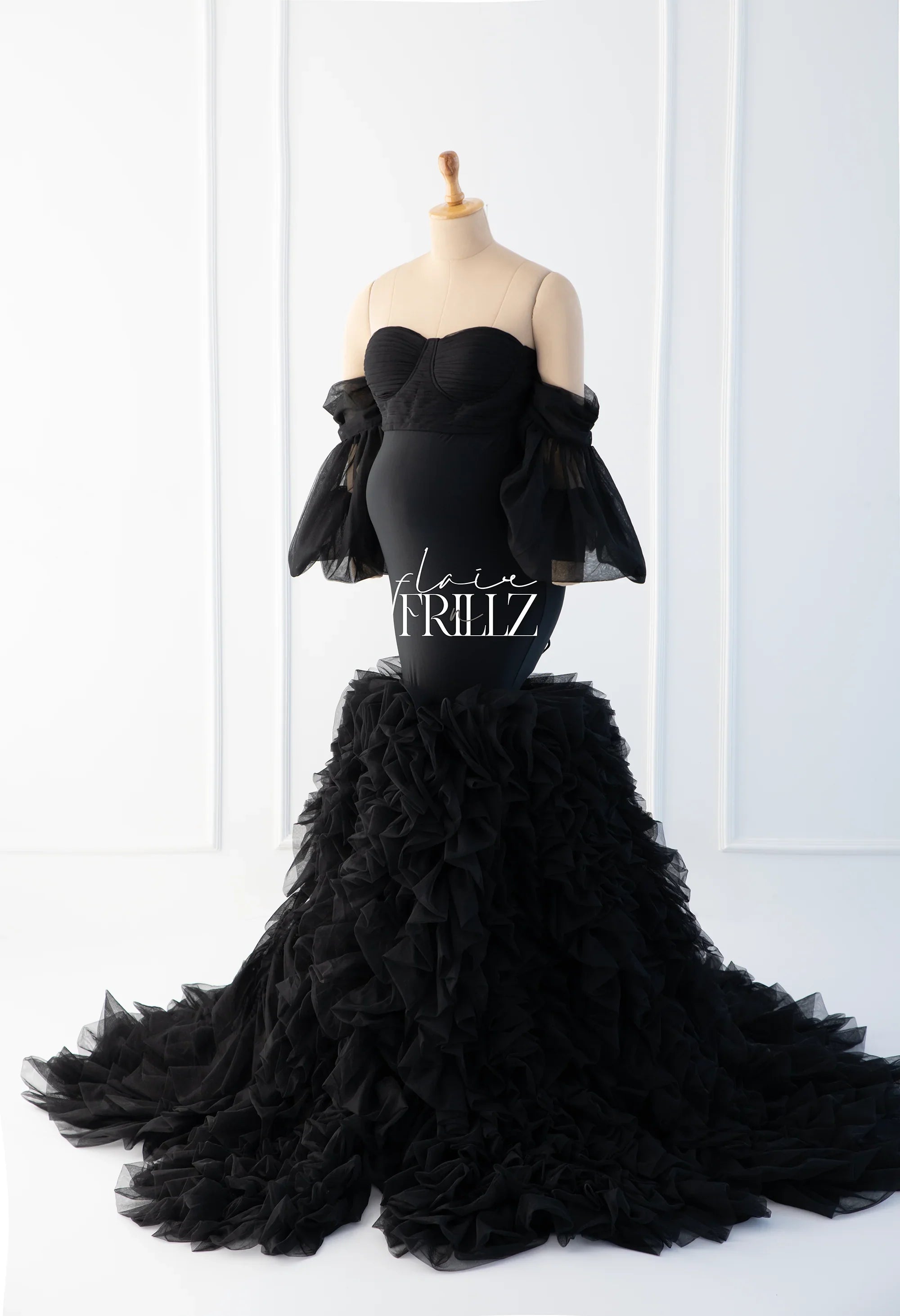 Elegant black maternity gown with ruffled tulle skirt and off-shoulder sleeves on mannequin