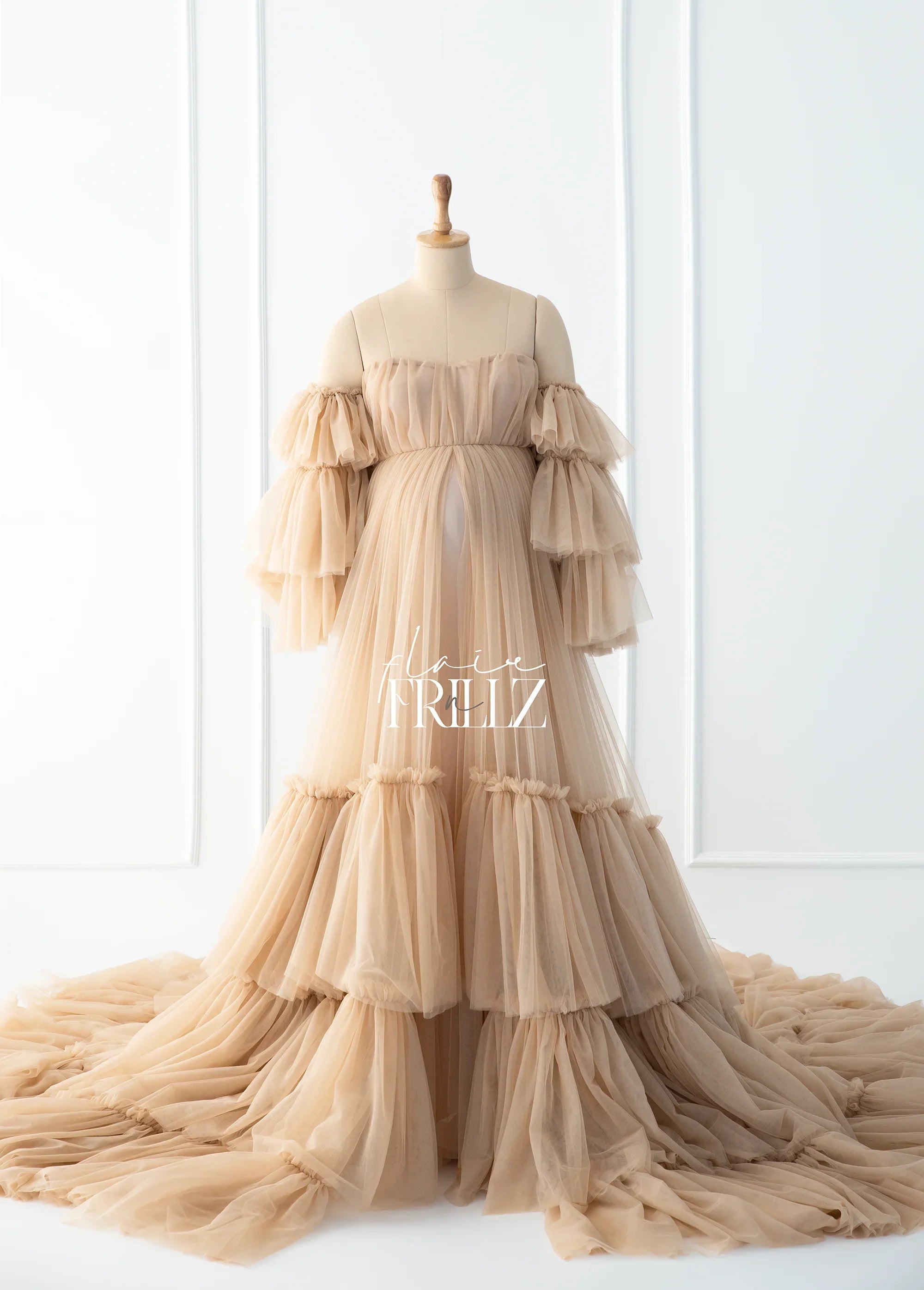 Beige ruffled maternity gown with layered tulle skirt and off-shoulder sleeves on mannequin