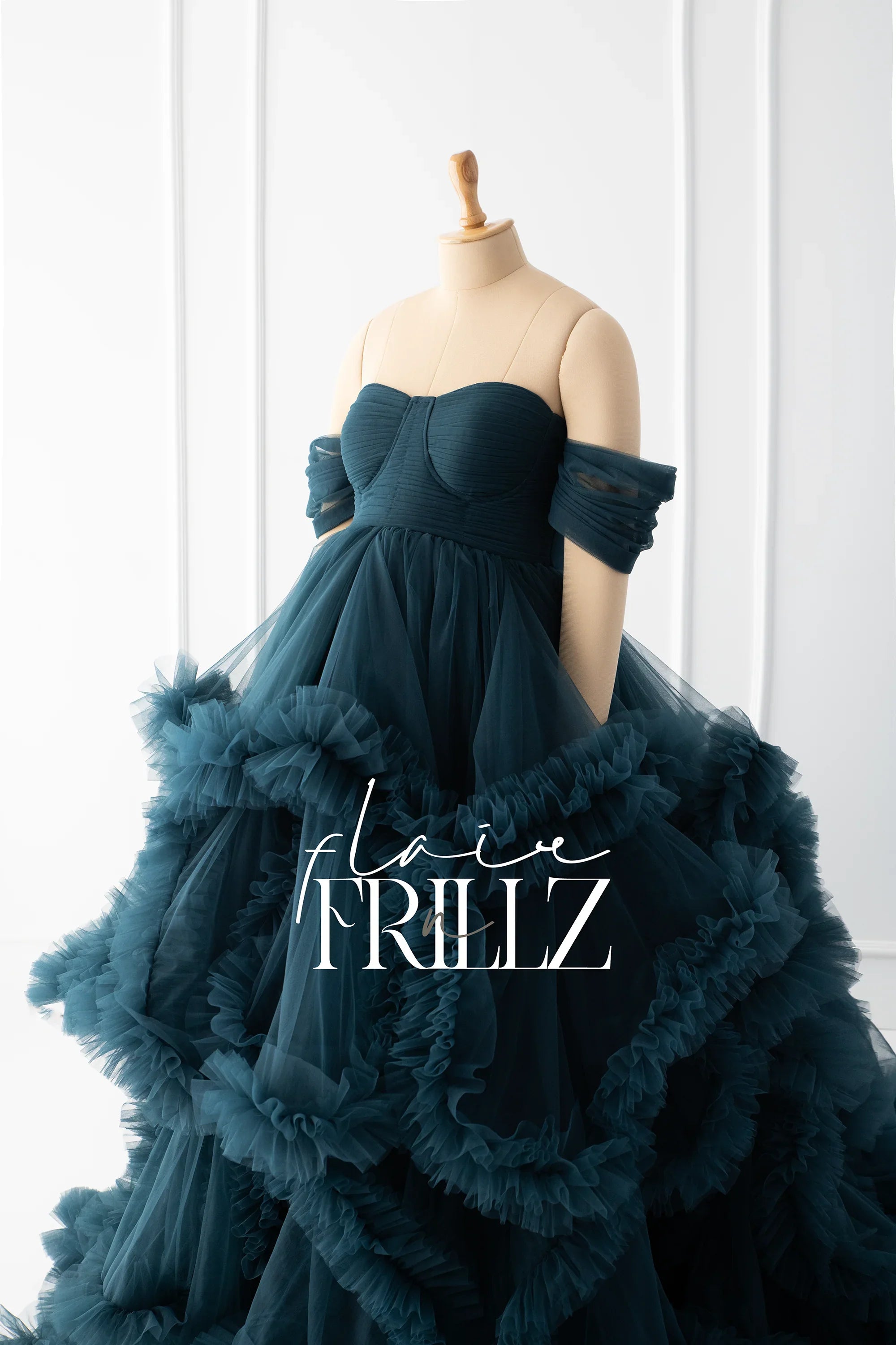 Elegant dark teal maternity gown with ruffled tulle skirt and off-shoulder sleeves on mannequin