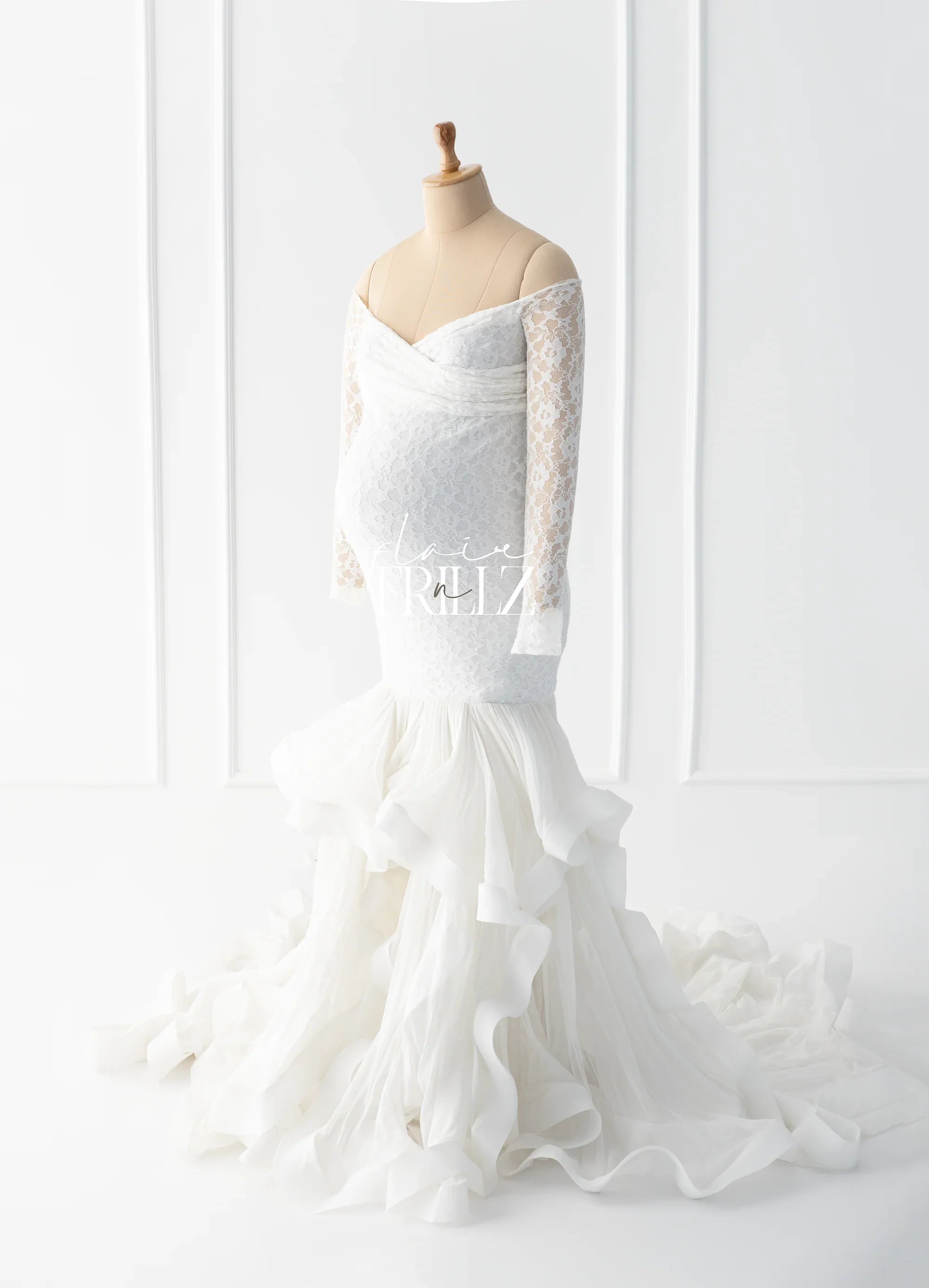 White lace maternity gown with off-shoulder sleeves and ruffled mermaid train on mannequin
