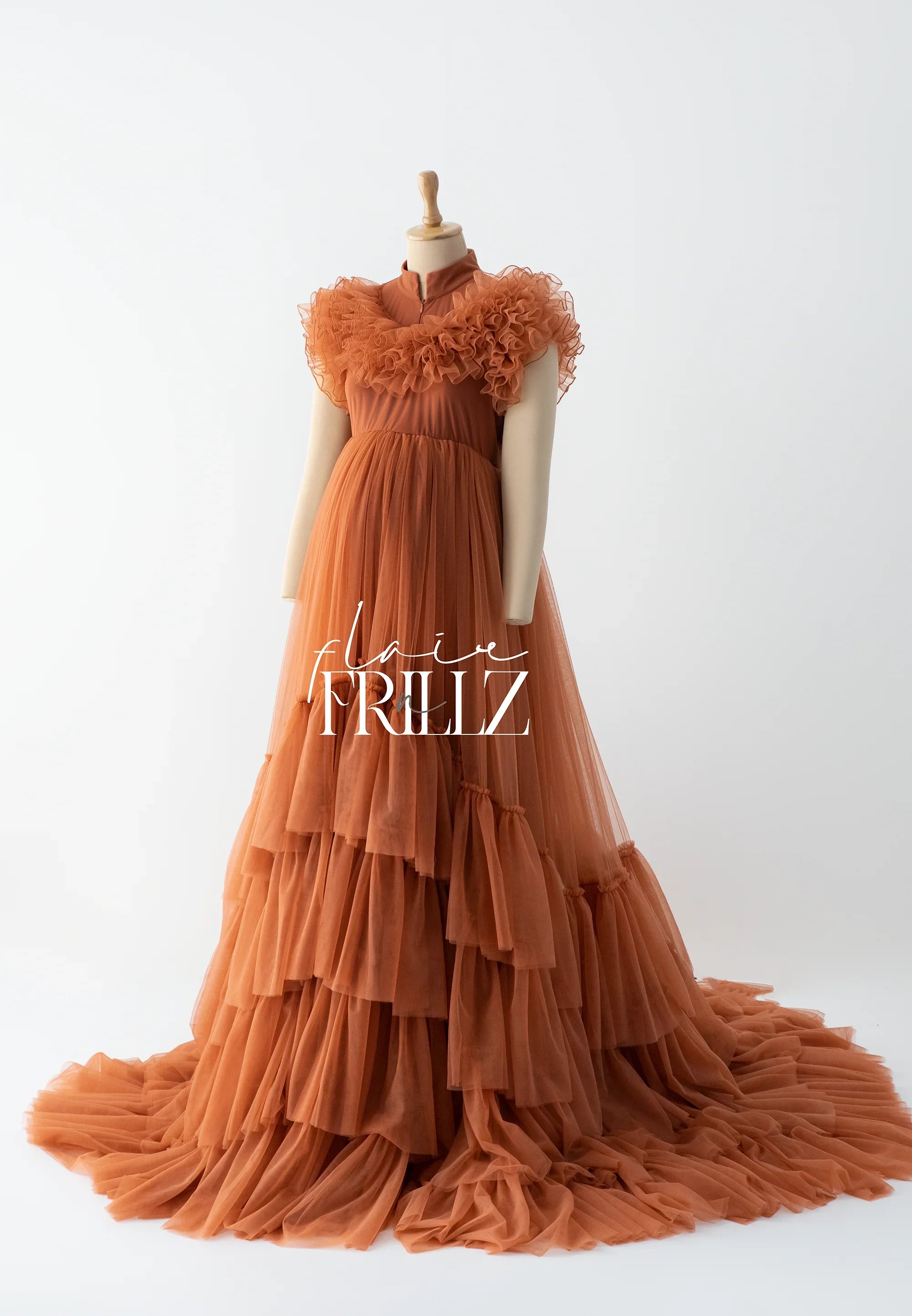 Rust orange ruffled maternity gown with layered tulle skirt on mannequin, elegant pregnancy dress