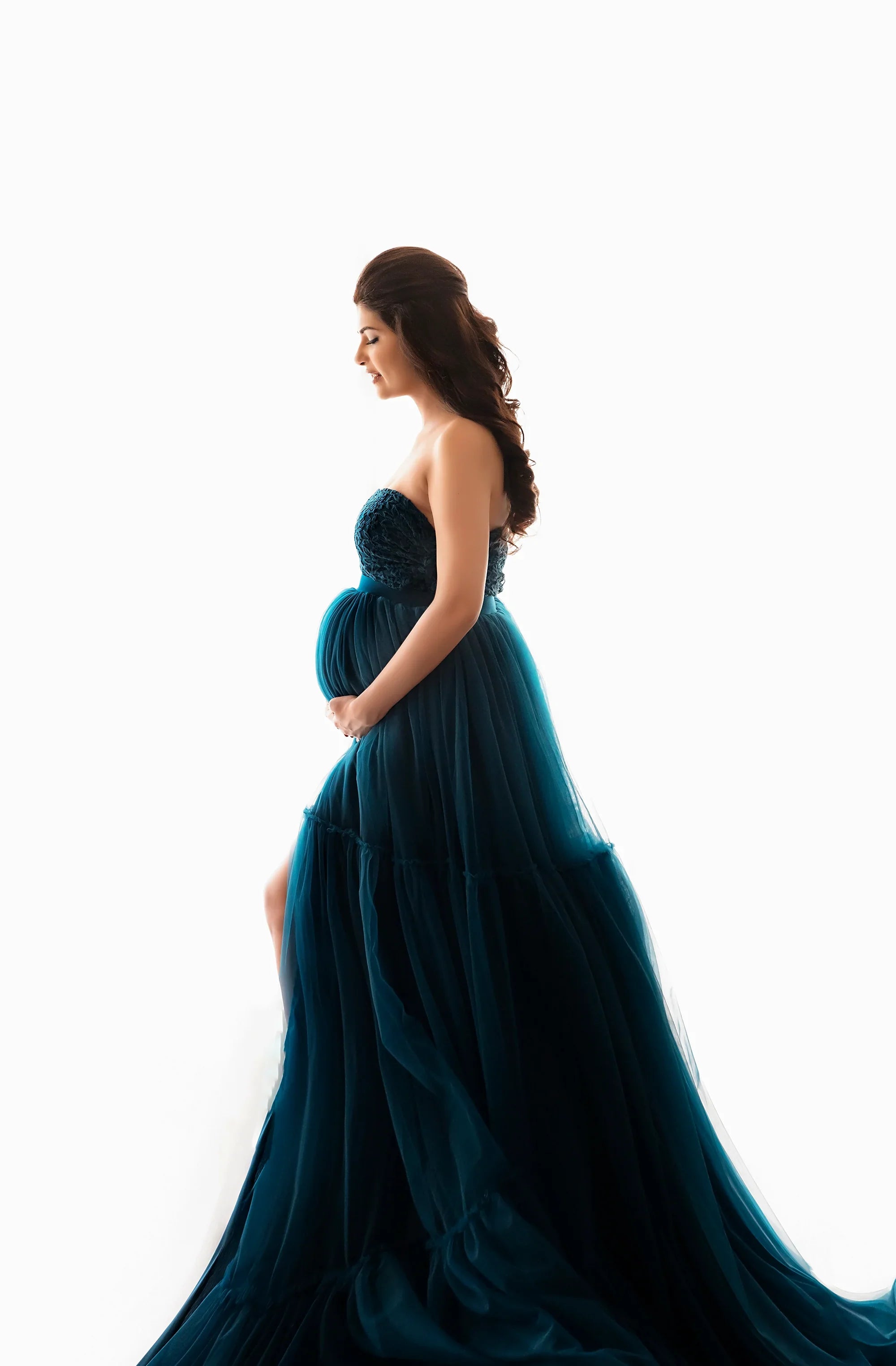 Pregnant woman in elegant blue strapless maternity gown with tulle skirt