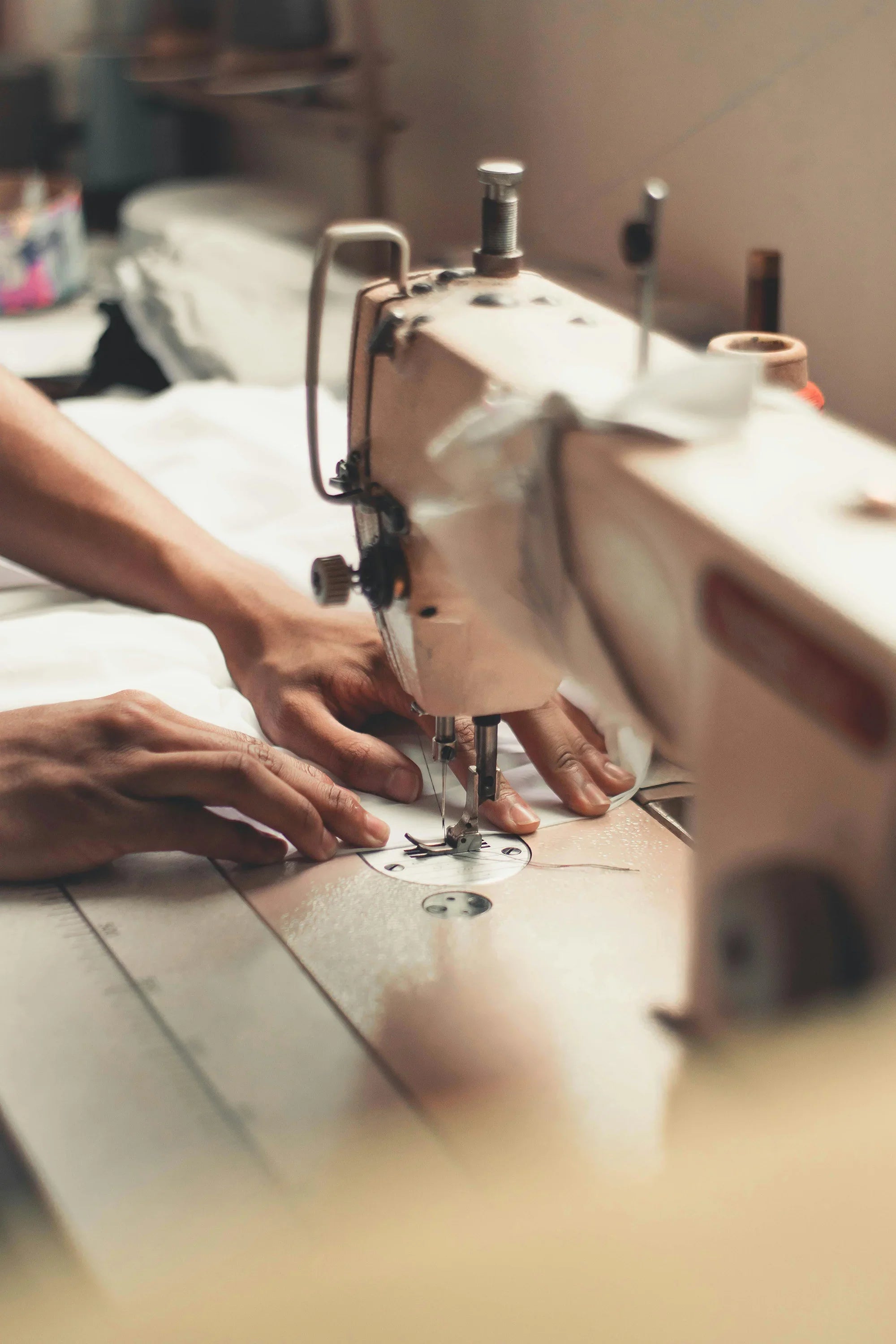 Hands sewing white fabric on a machine for maternity wear