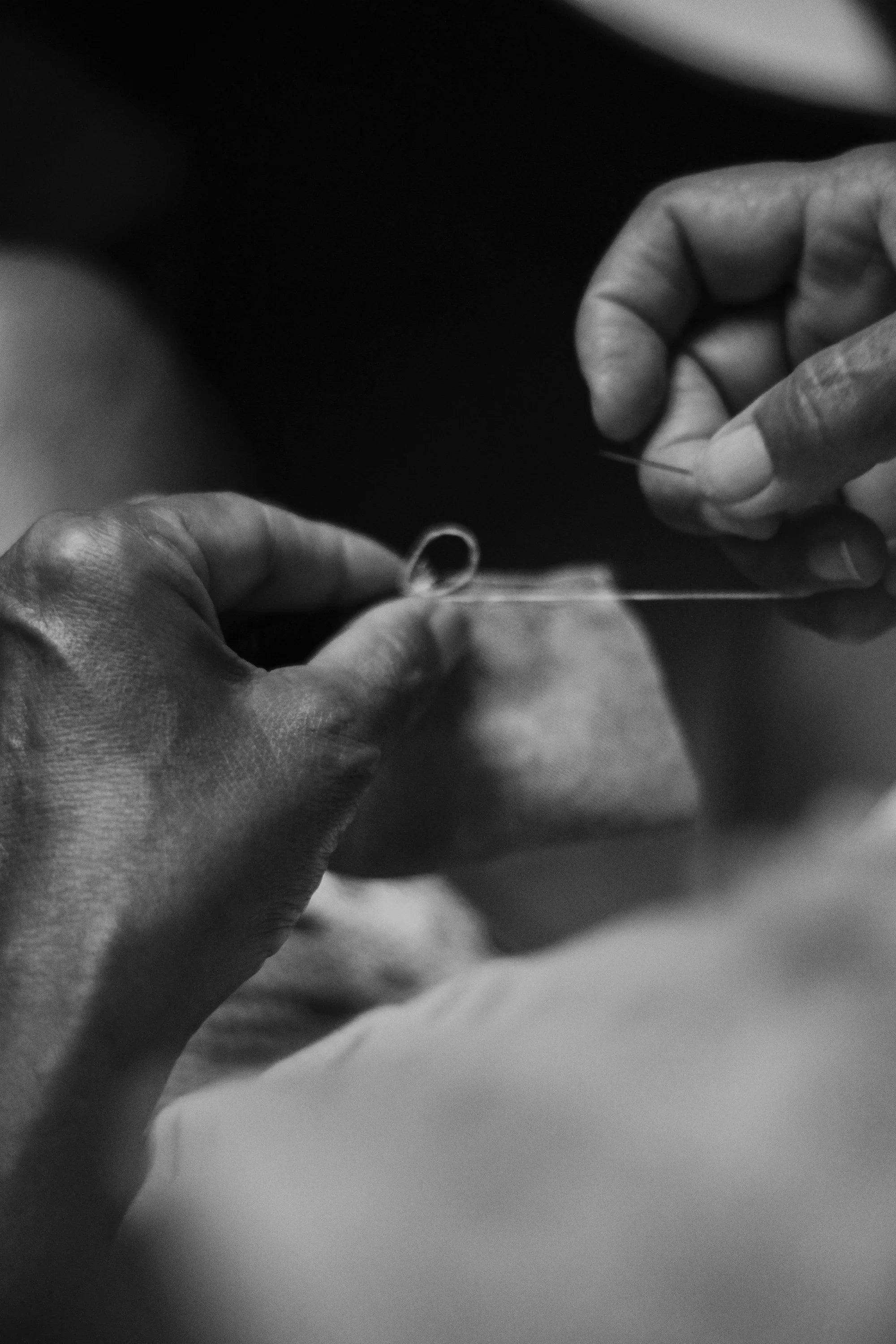 Close-up of hands sewing fabric, highlighting craftsmanship in maternity wear design