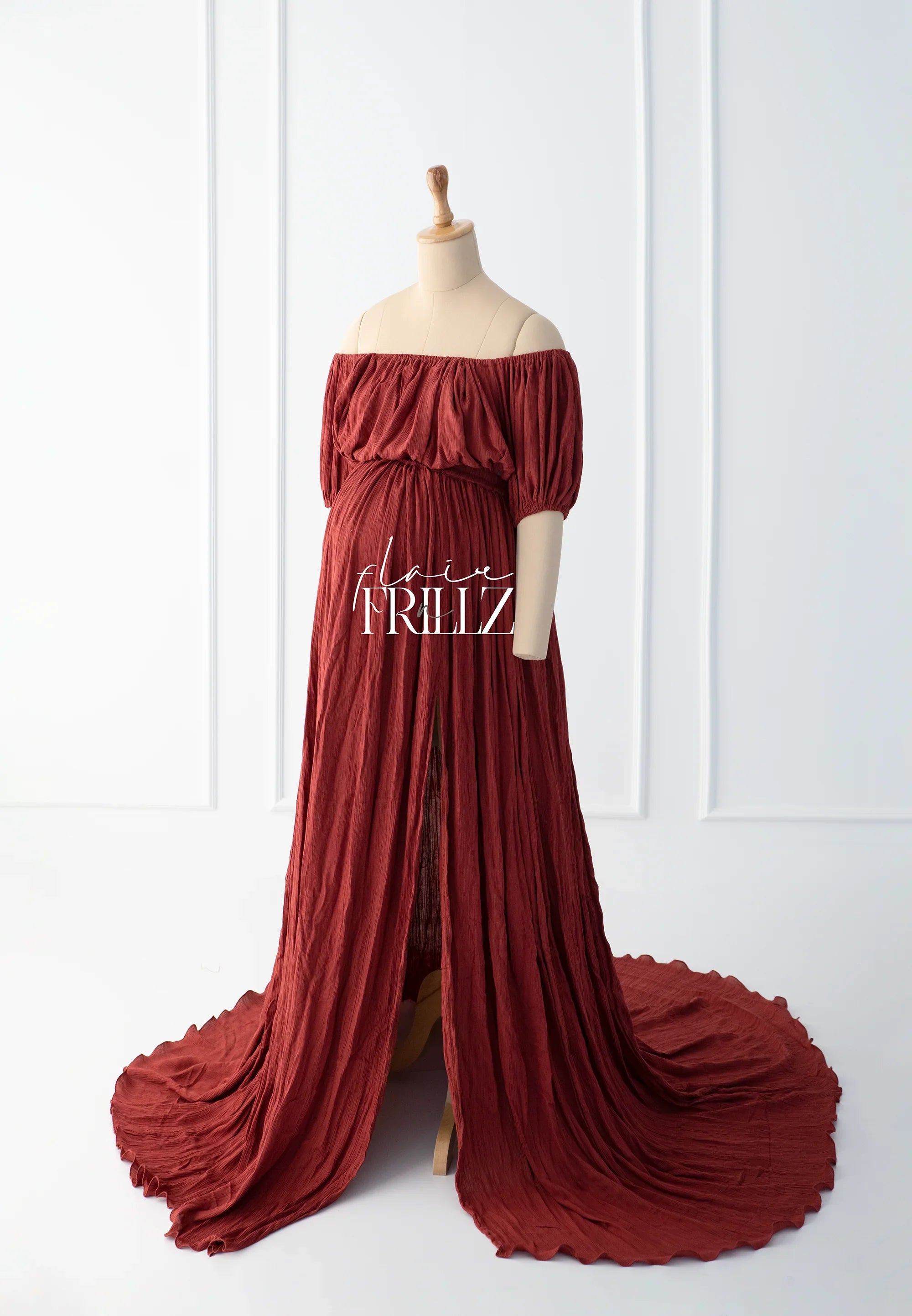 Rust boho off-shoulder maternity gown with puff sleeves and flowing skirt on mannequin