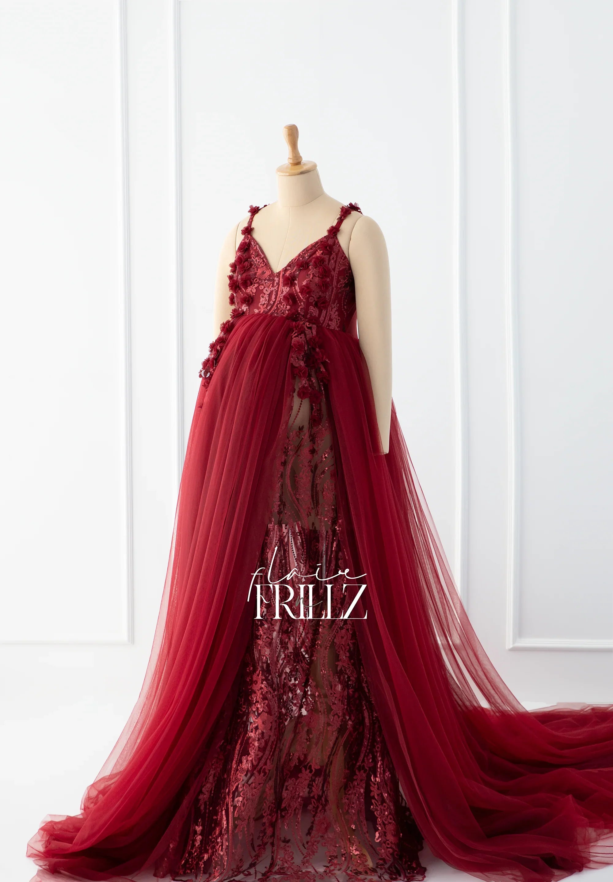 Elegant burgundy maternity gown with lace and tulle overlay on mannequin