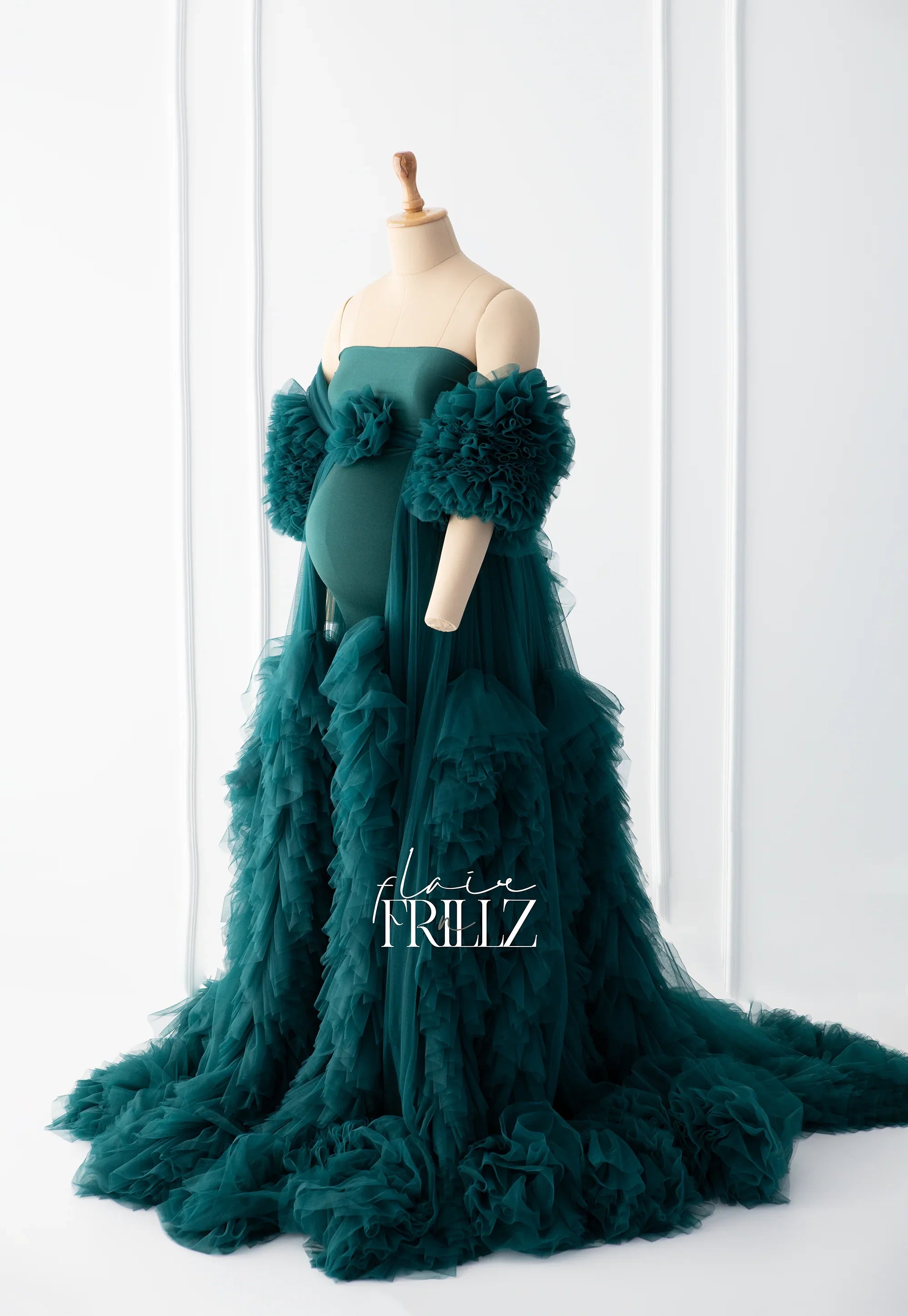 Teal ruffled maternity gown with dramatic tulle sleeves and flowing skirt on a mannequin
