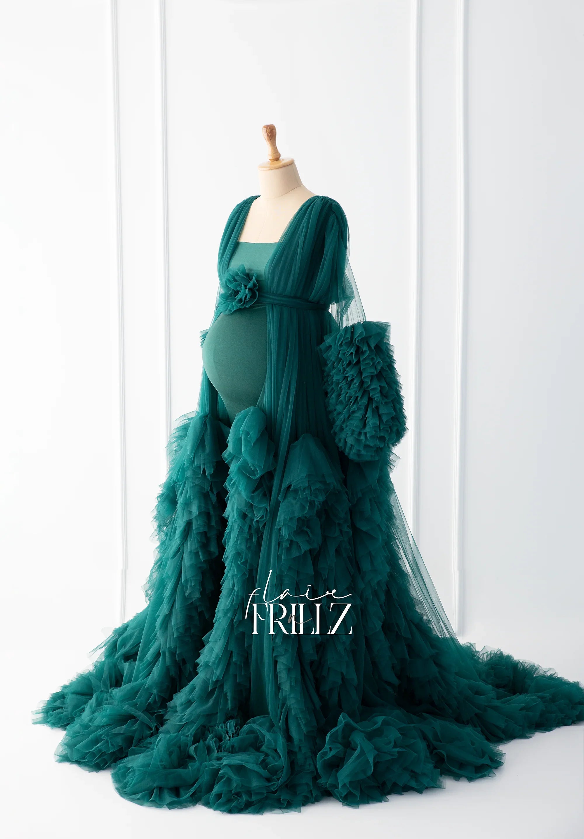 Elegant emerald green ruffled maternity gown with long train on mannequin