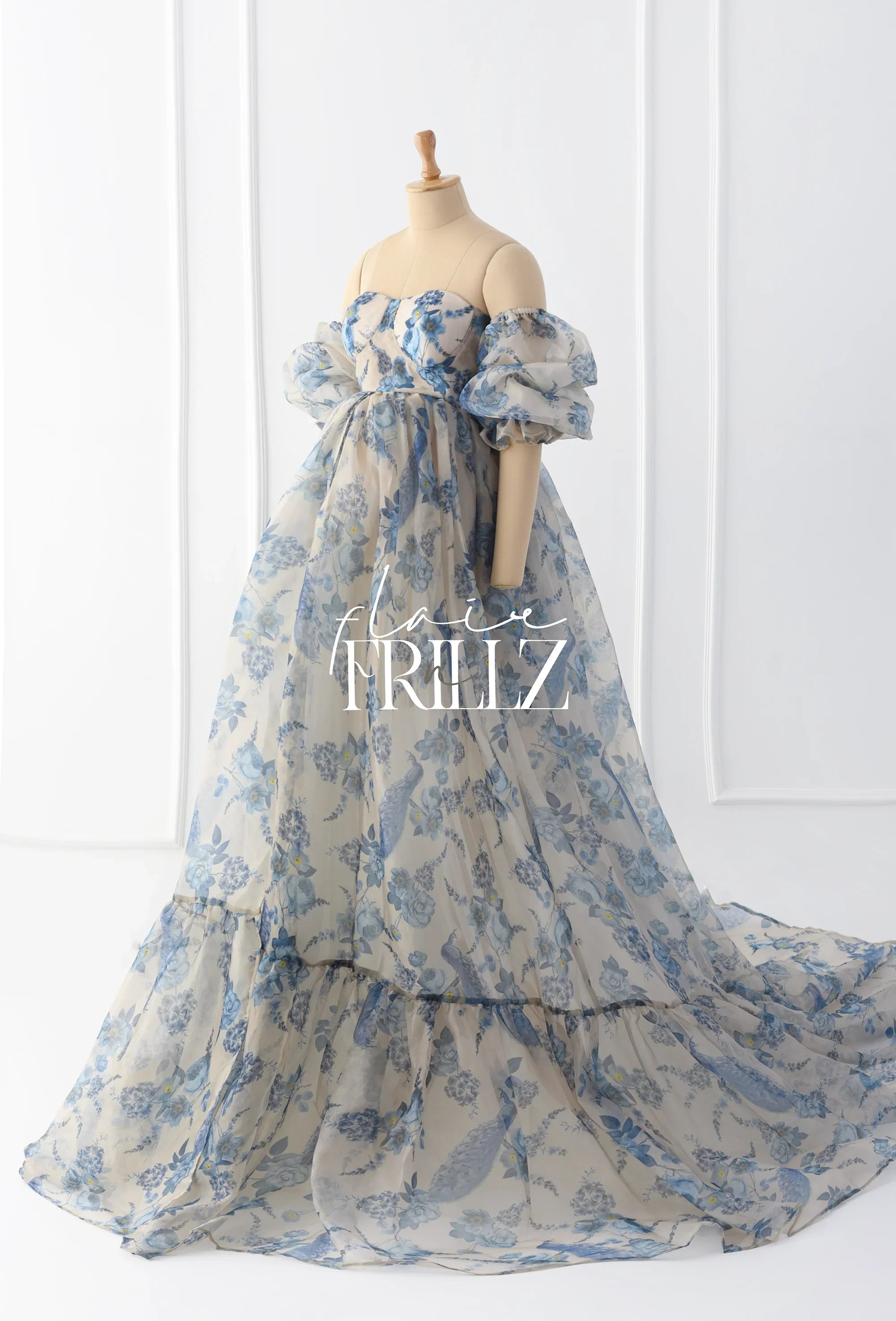 Sheer blue floral printed maternity gown with puff sleeves and a flowing train on mannequin