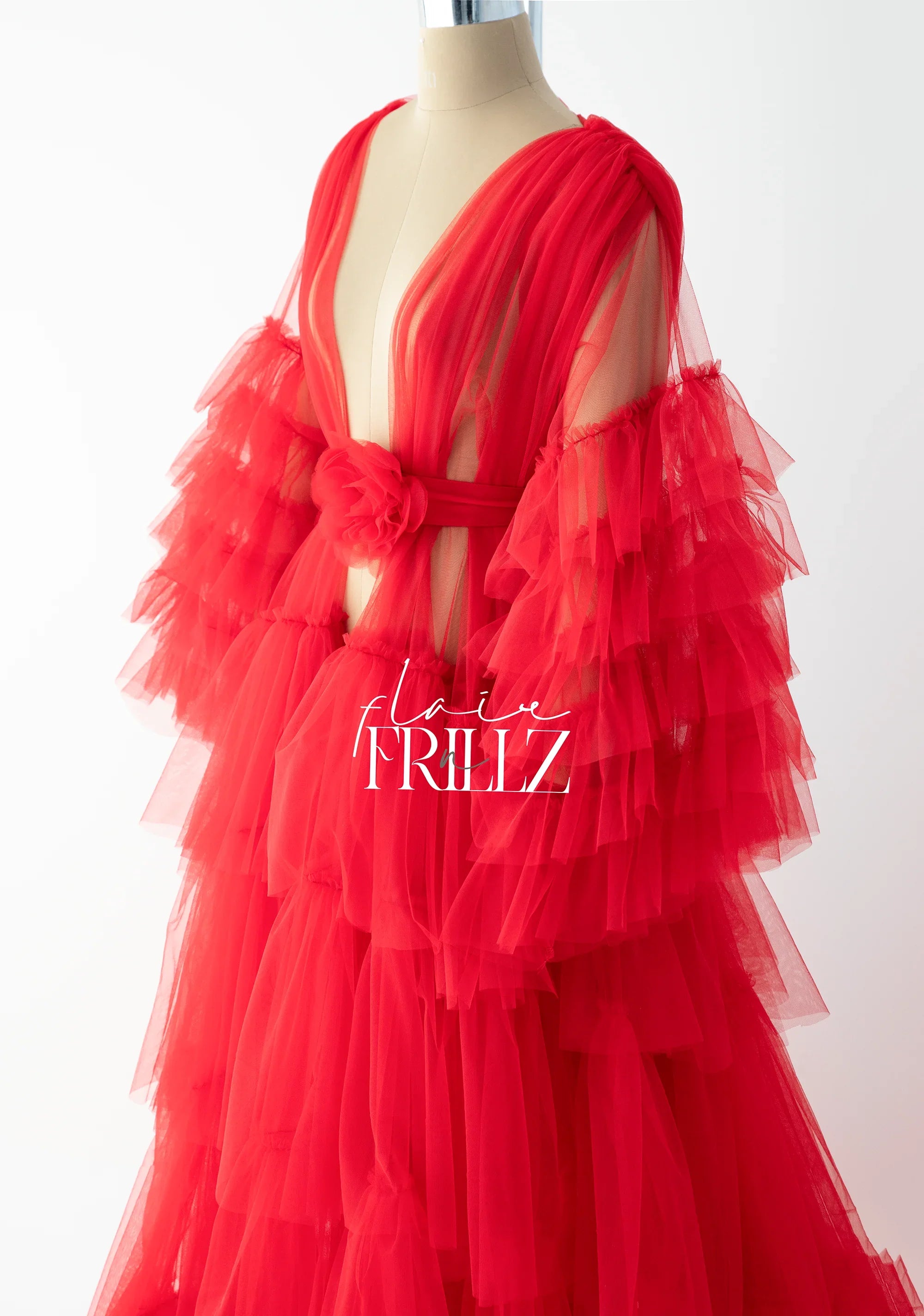 Red tulle maternity gown with ruffled sleeves and floral waist detail on a mannequin