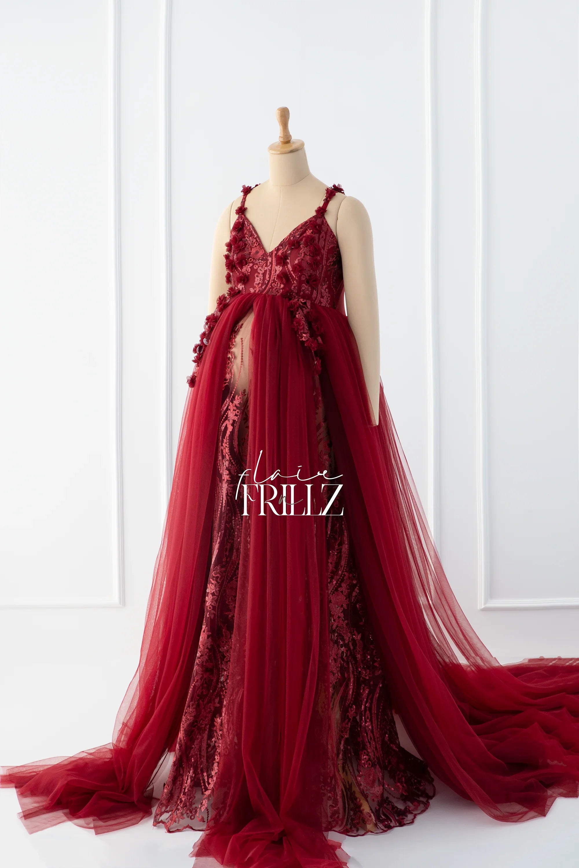 Elegant burgundy maternity gown with lace applique and tulle overlay on mannequin
