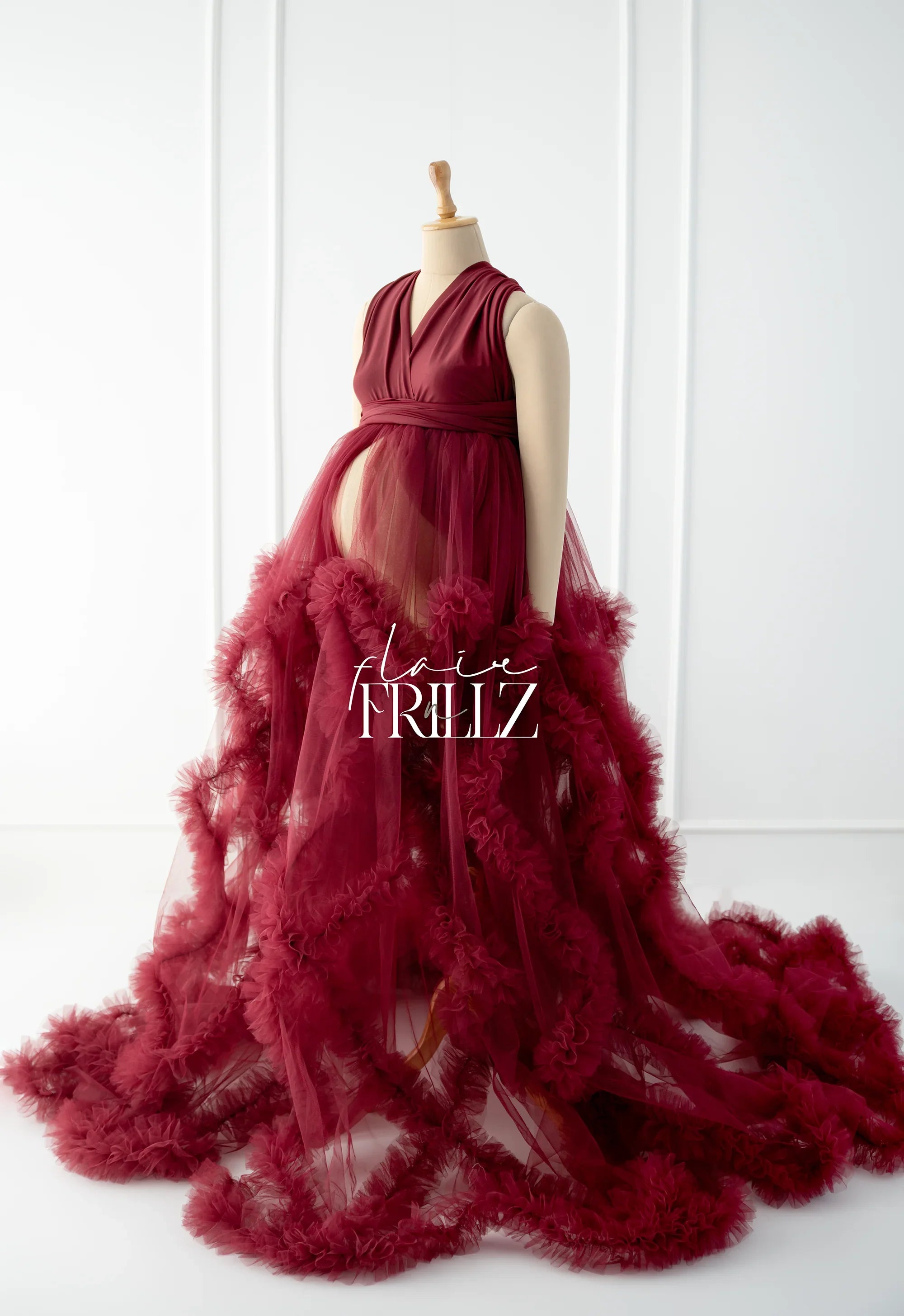 Burgundy maternity gown with flowing ruffled tulle skirt on mannequin, elegant style