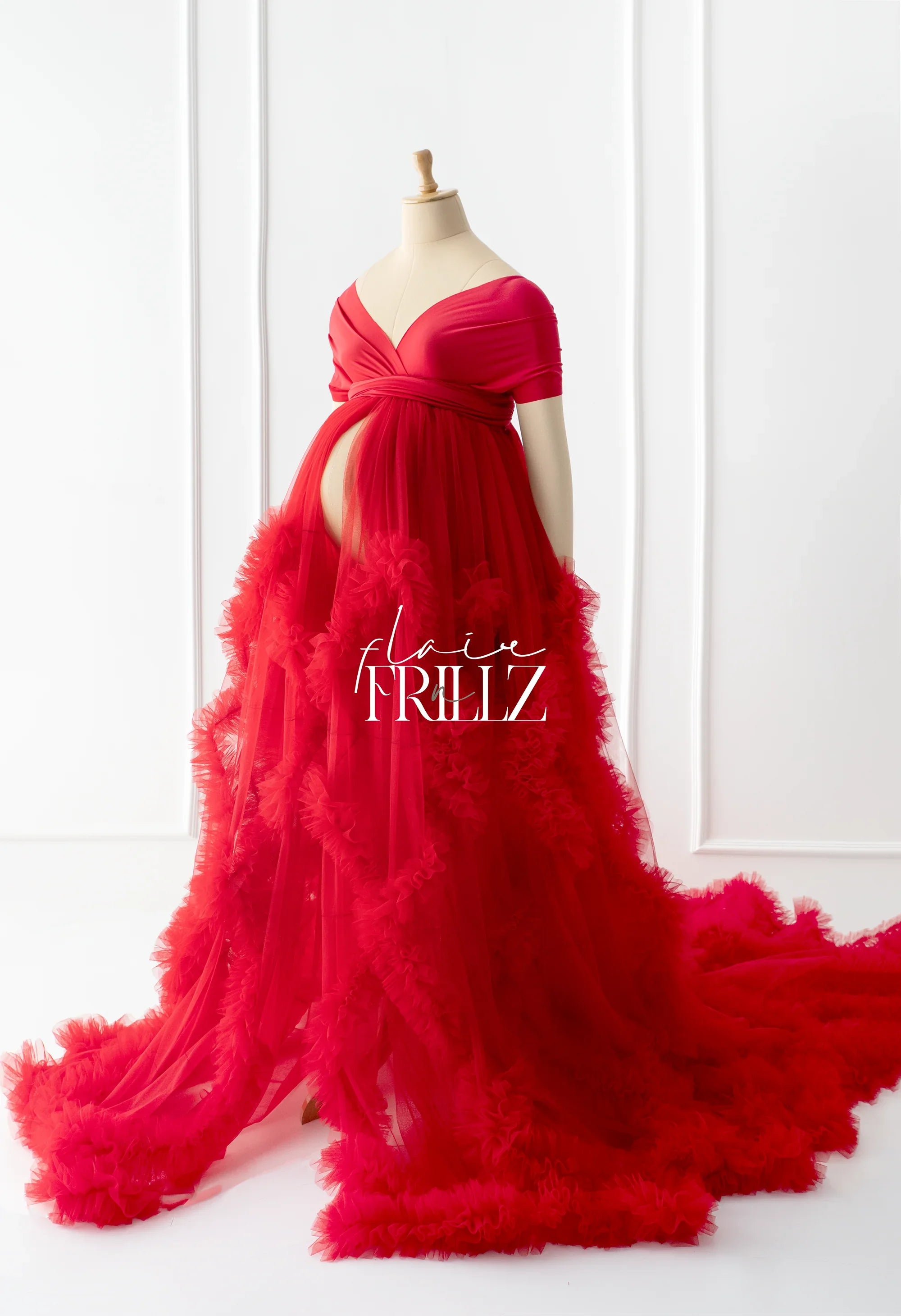 Elegant red maternity gown with ruffled tulle skirt on mannequin, off-shoulder style