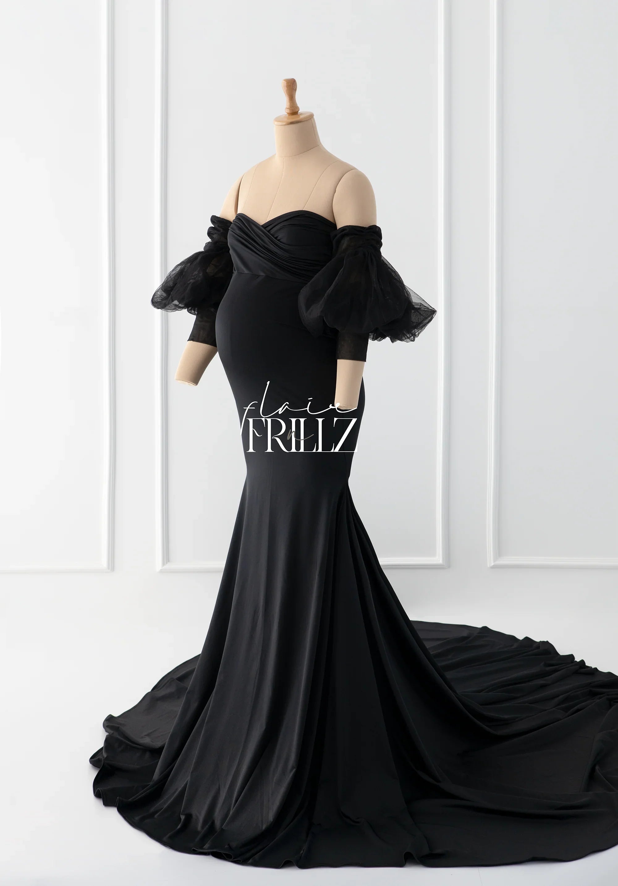 Elegant black maternity gown with sheer puff sleeves and long train, displayed on mannequin