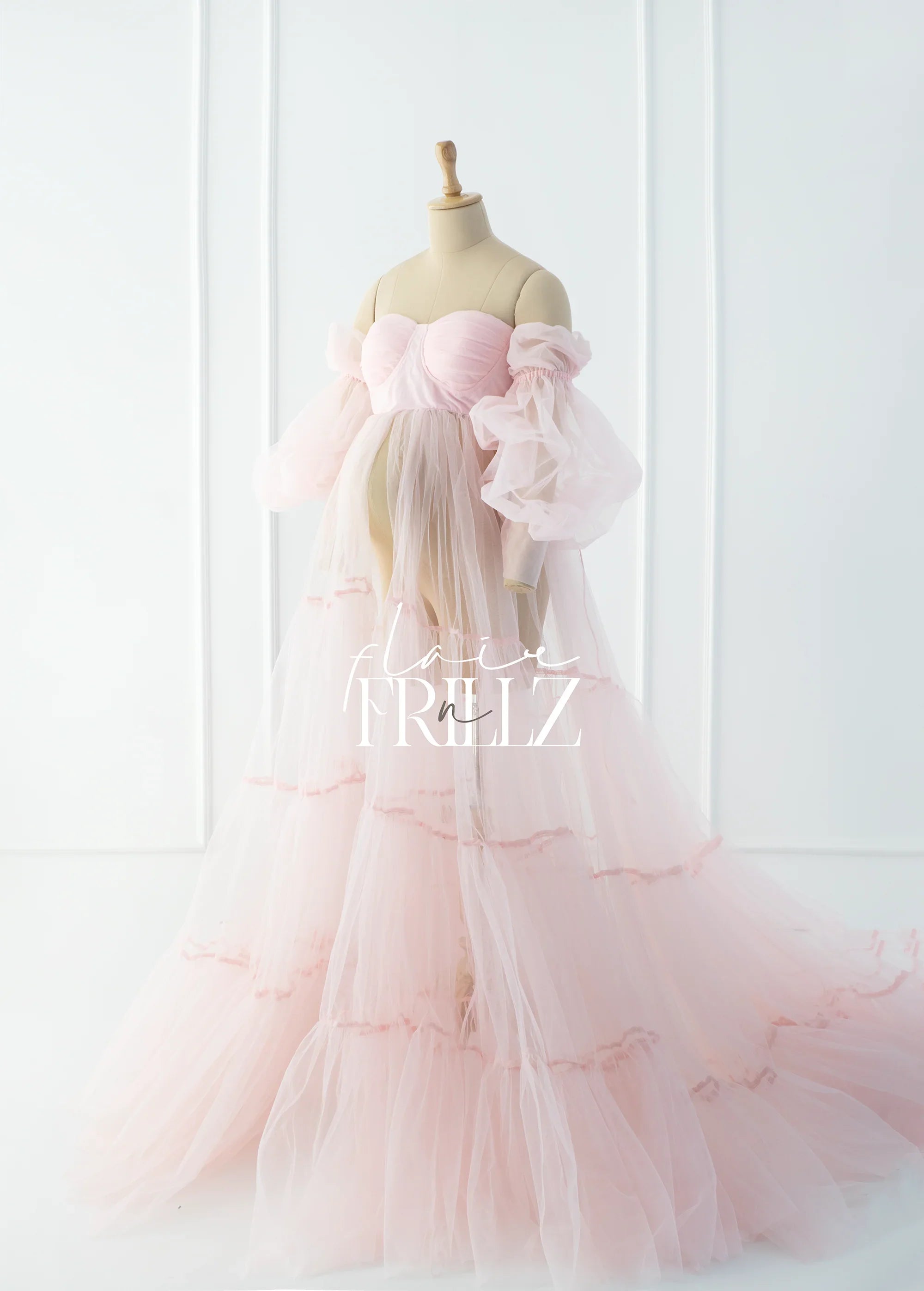 Light pink sheer maternity gown with off-shoulder puffy sleeves displayed on mannequin