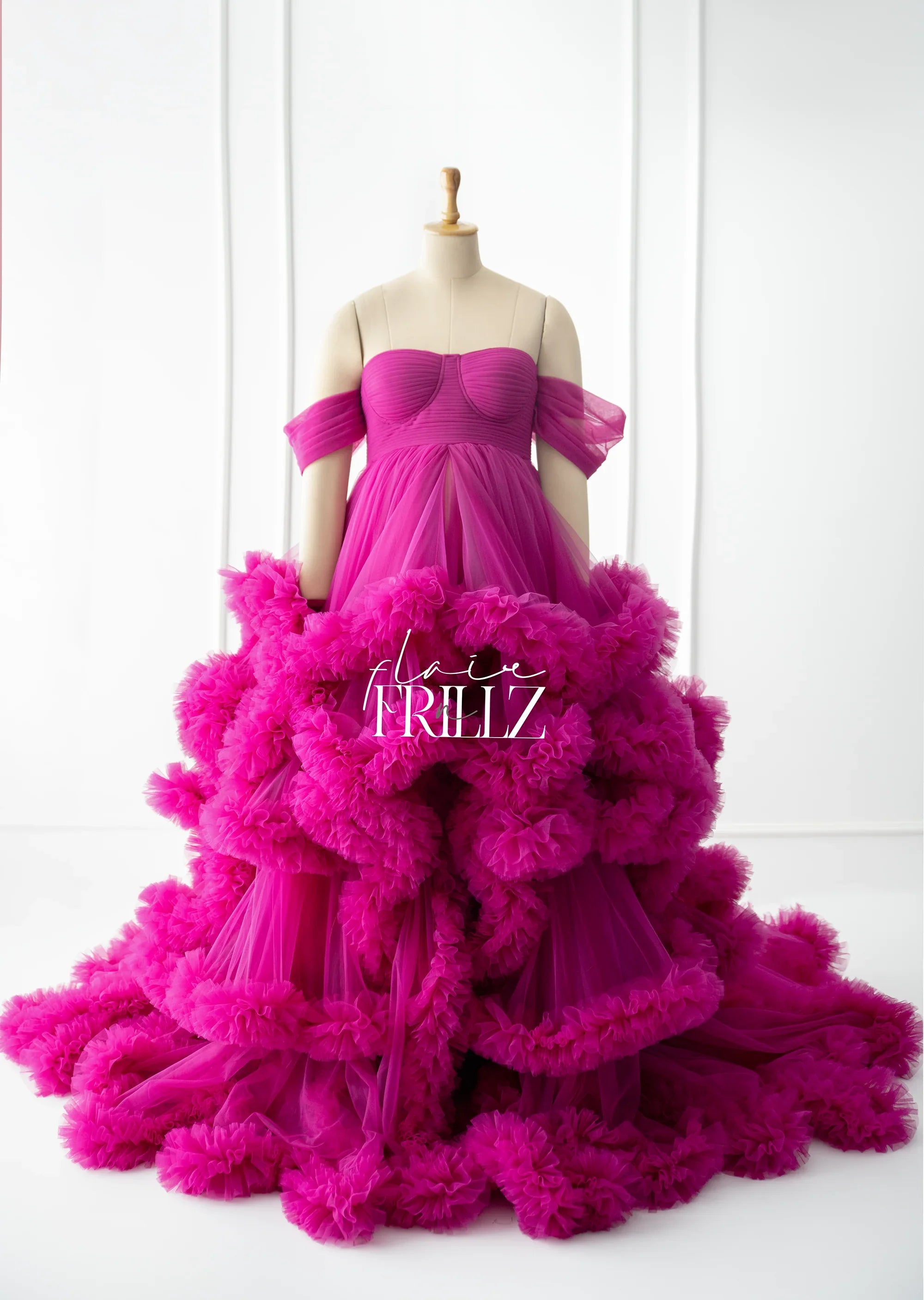 Vibrant magenta off-shoulder maternity gown with ruffled tulle layers on dress form