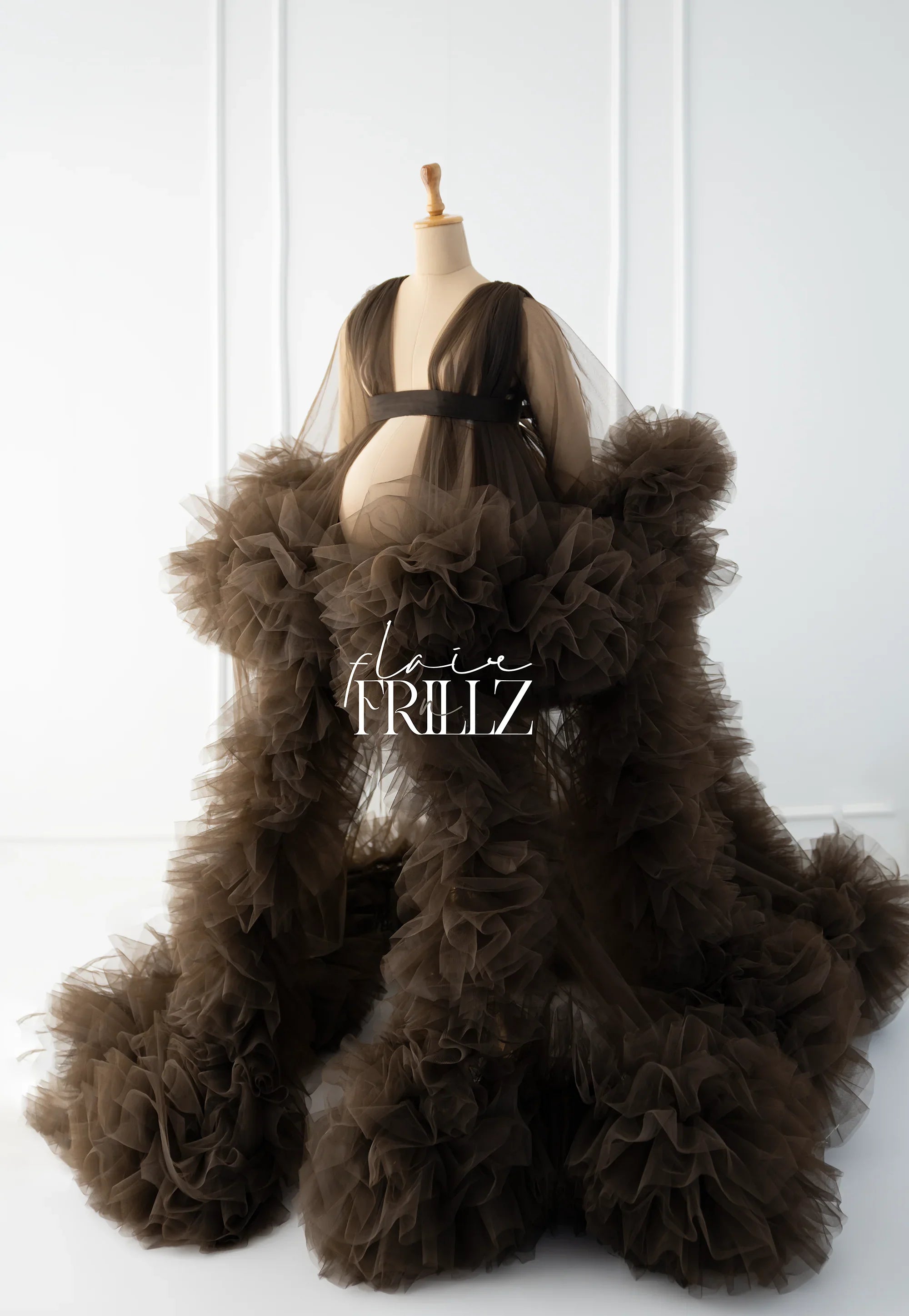Sheer brown ruffled maternity gown with dramatic tulle layers on a dress form