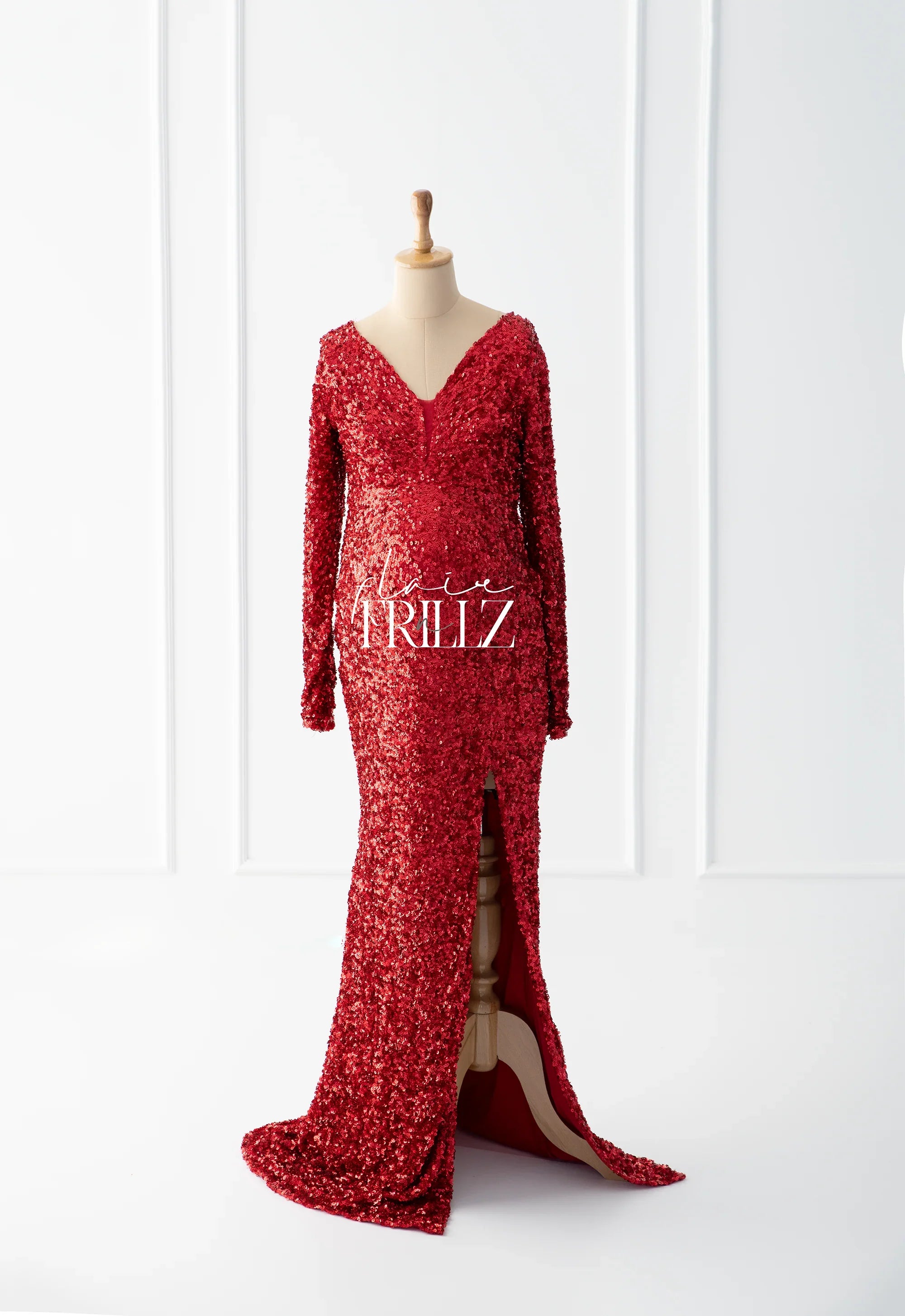 Red sequin maternity gown with long sleeves, deep V-neck, and front slit on a mannequin.