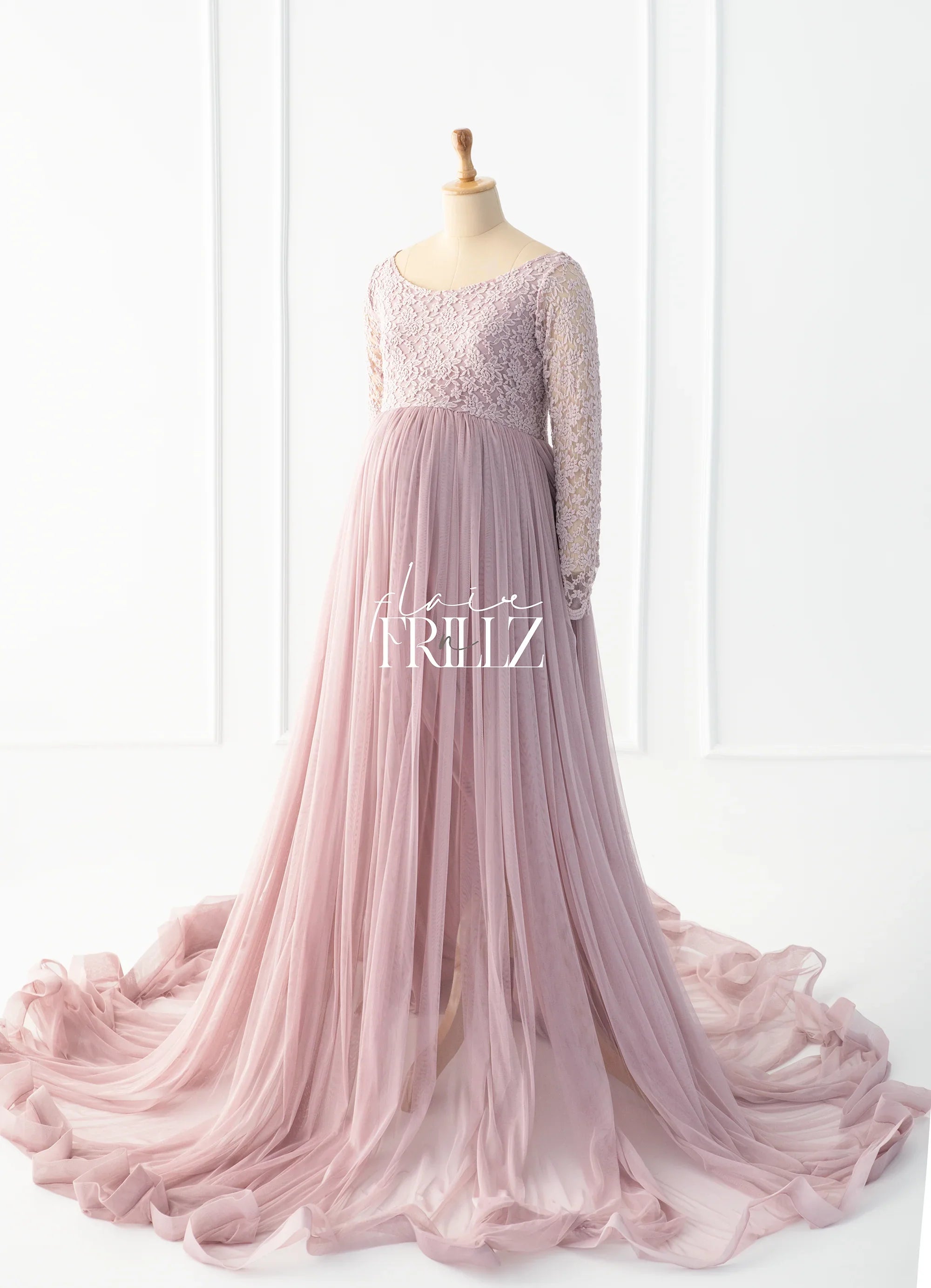 Long-sleeve blush pink lace maternity gown with flowing tulle skirt on mannequin