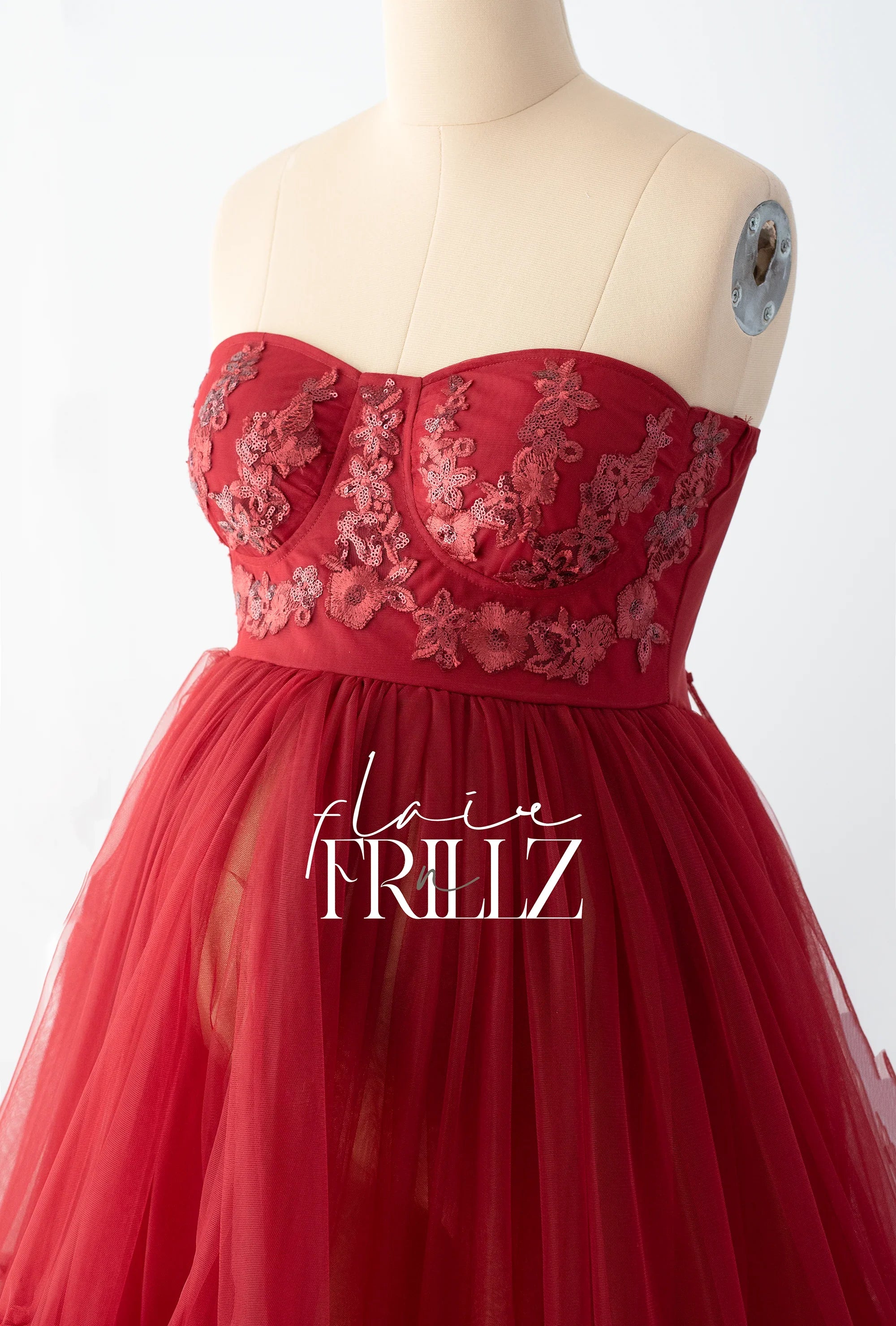 Red strapless maternity gown with floral lace bodice and tulle skirt on mannequin