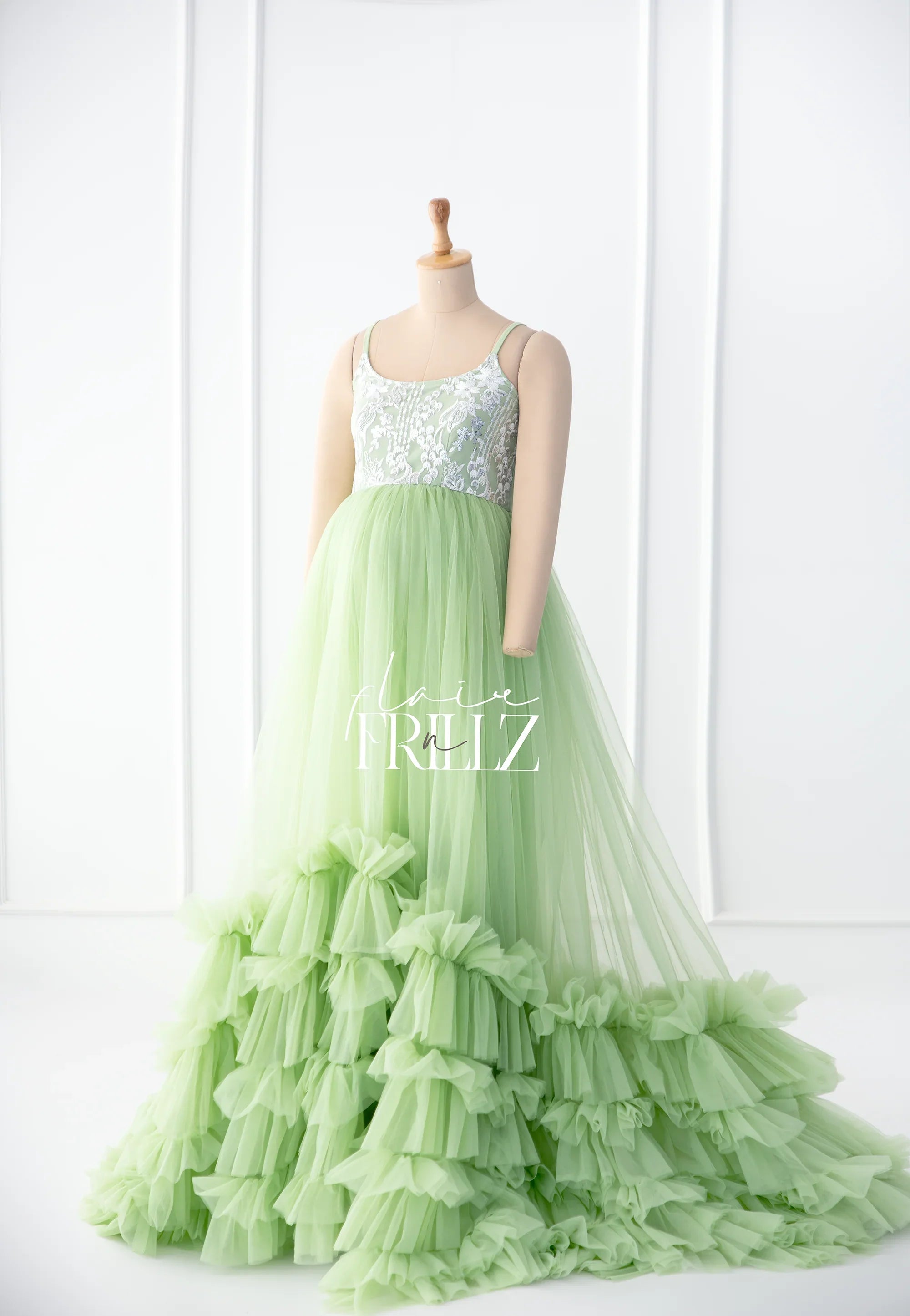 Light green maternity gown with lace bodice and ruffled tulle skirt on mannequin