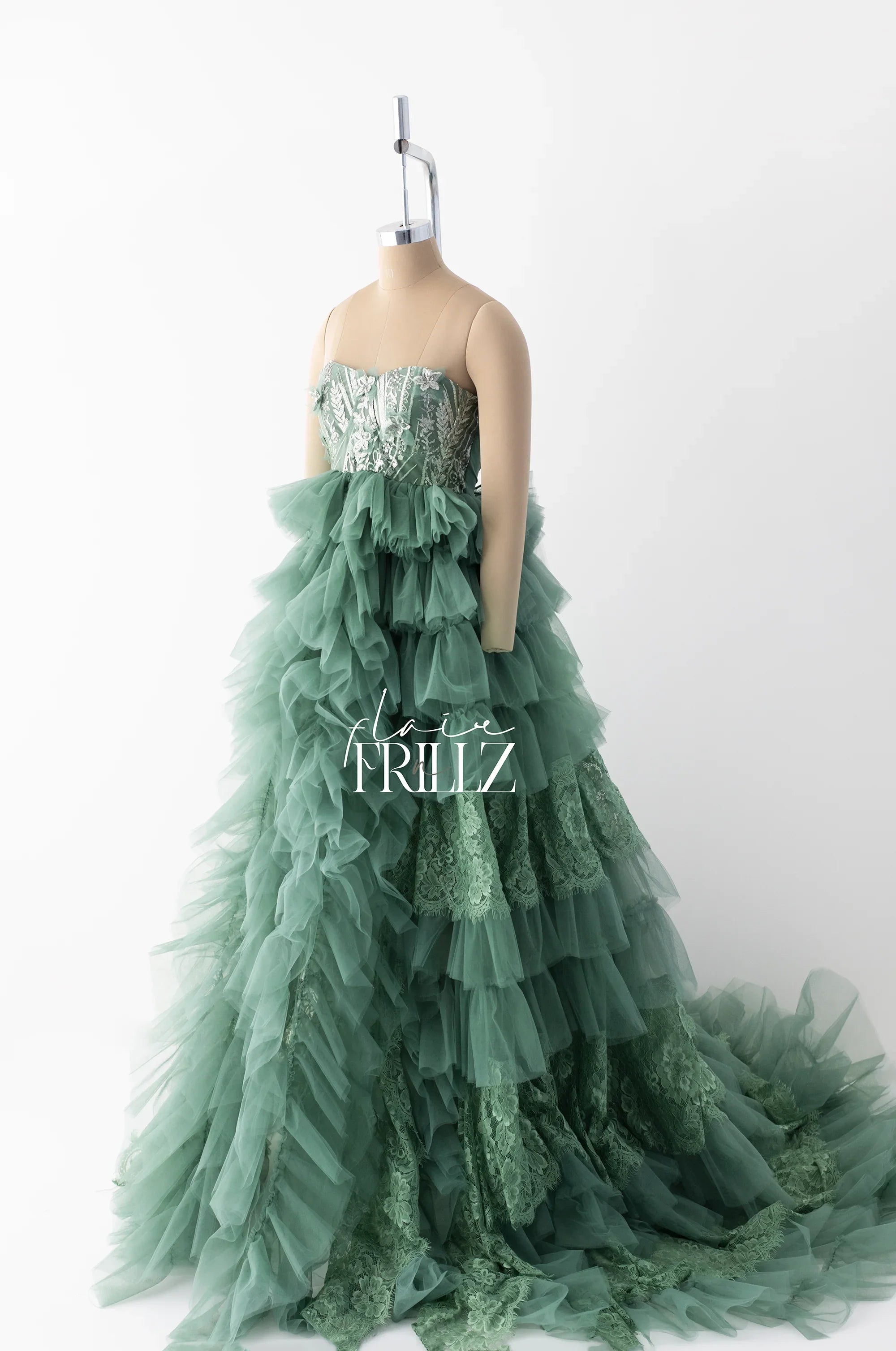Elegant green maternity gown with ruffled tulle layers and lace details on mannequin